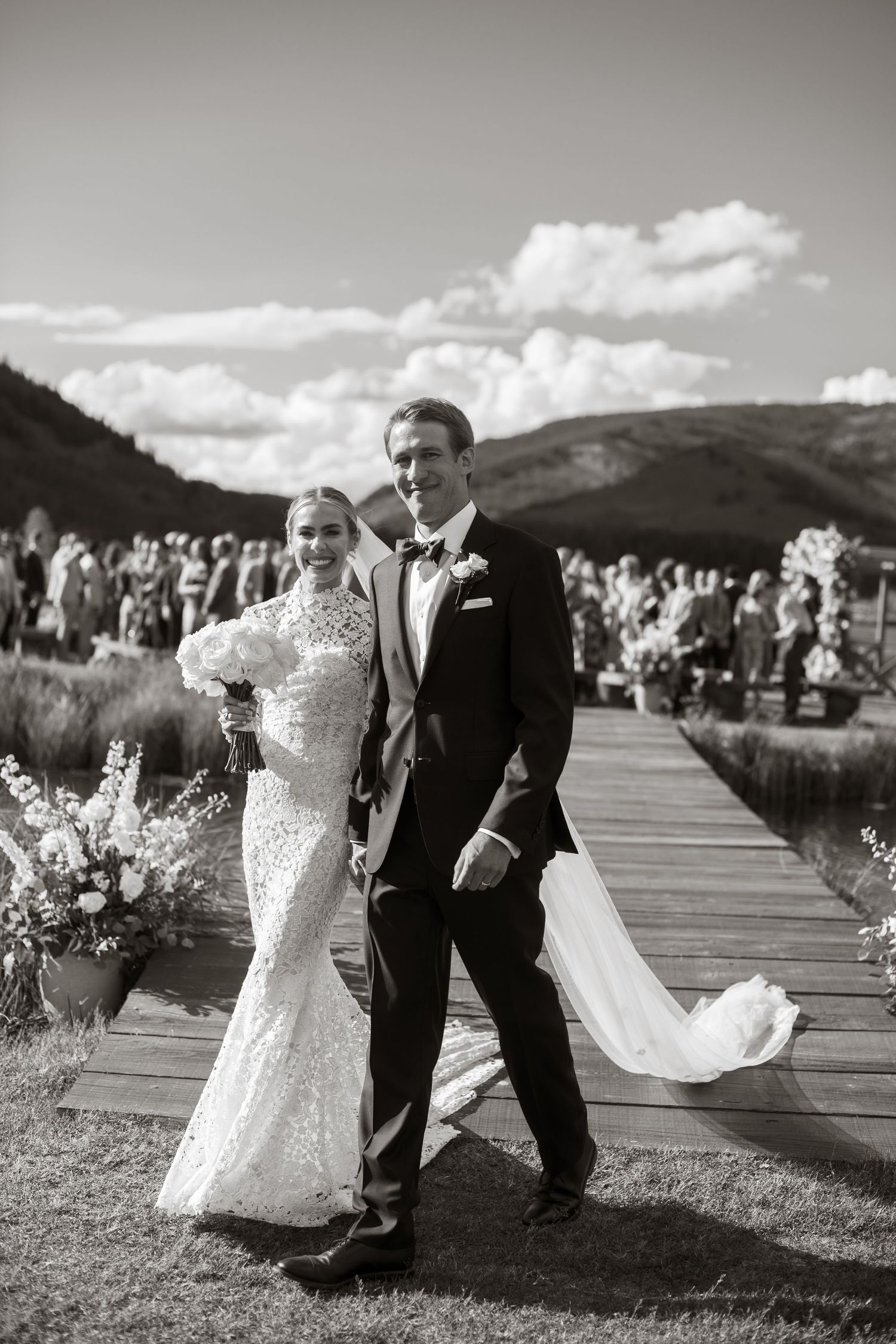 Black and white sequence of newlyweds dancing playfully on a wooden deck with mountain views.