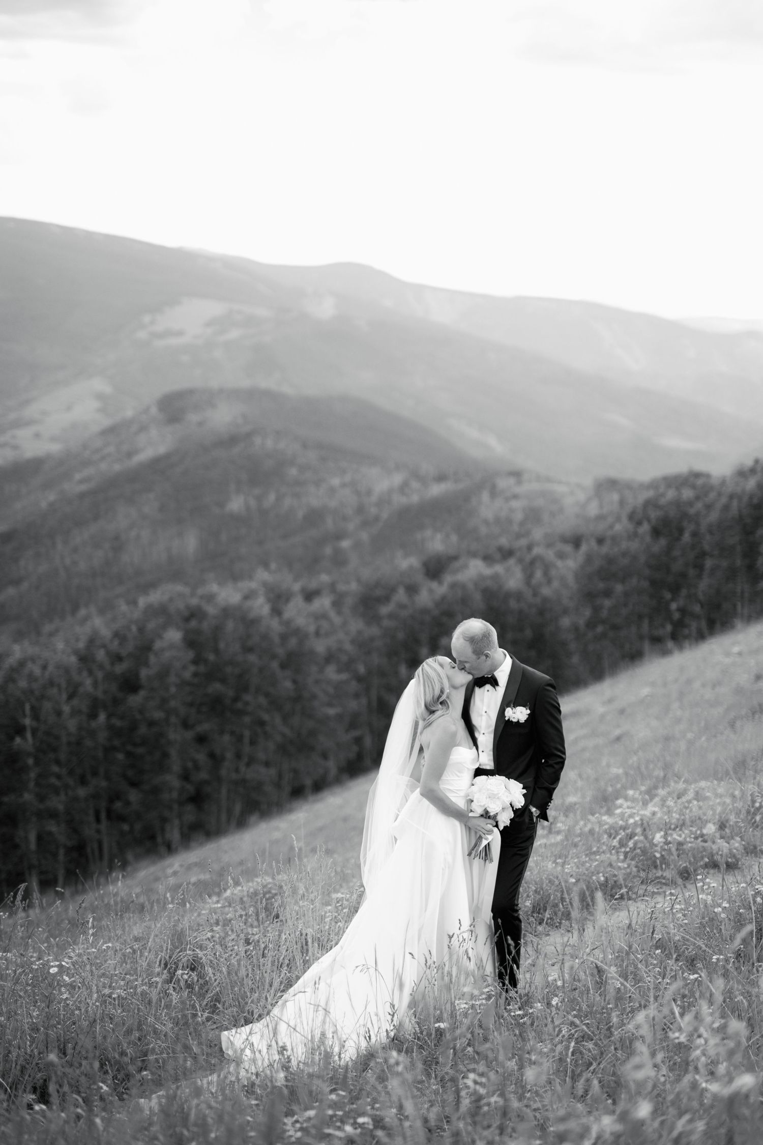 A romantic black and white wedding portrait in a mountain meadow.
