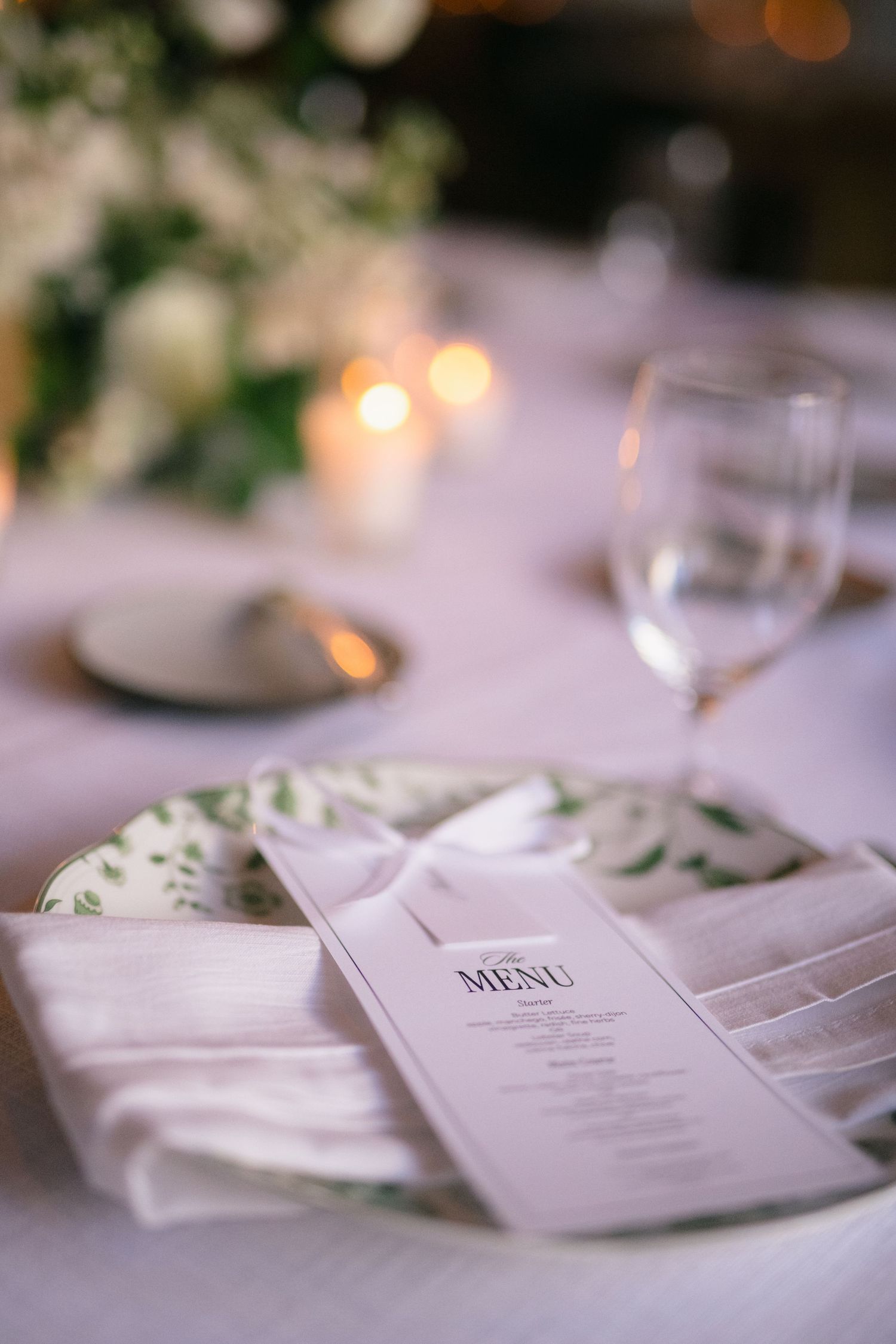 Wedding reception details with elegant menu cards and table settings in soft lighting.
