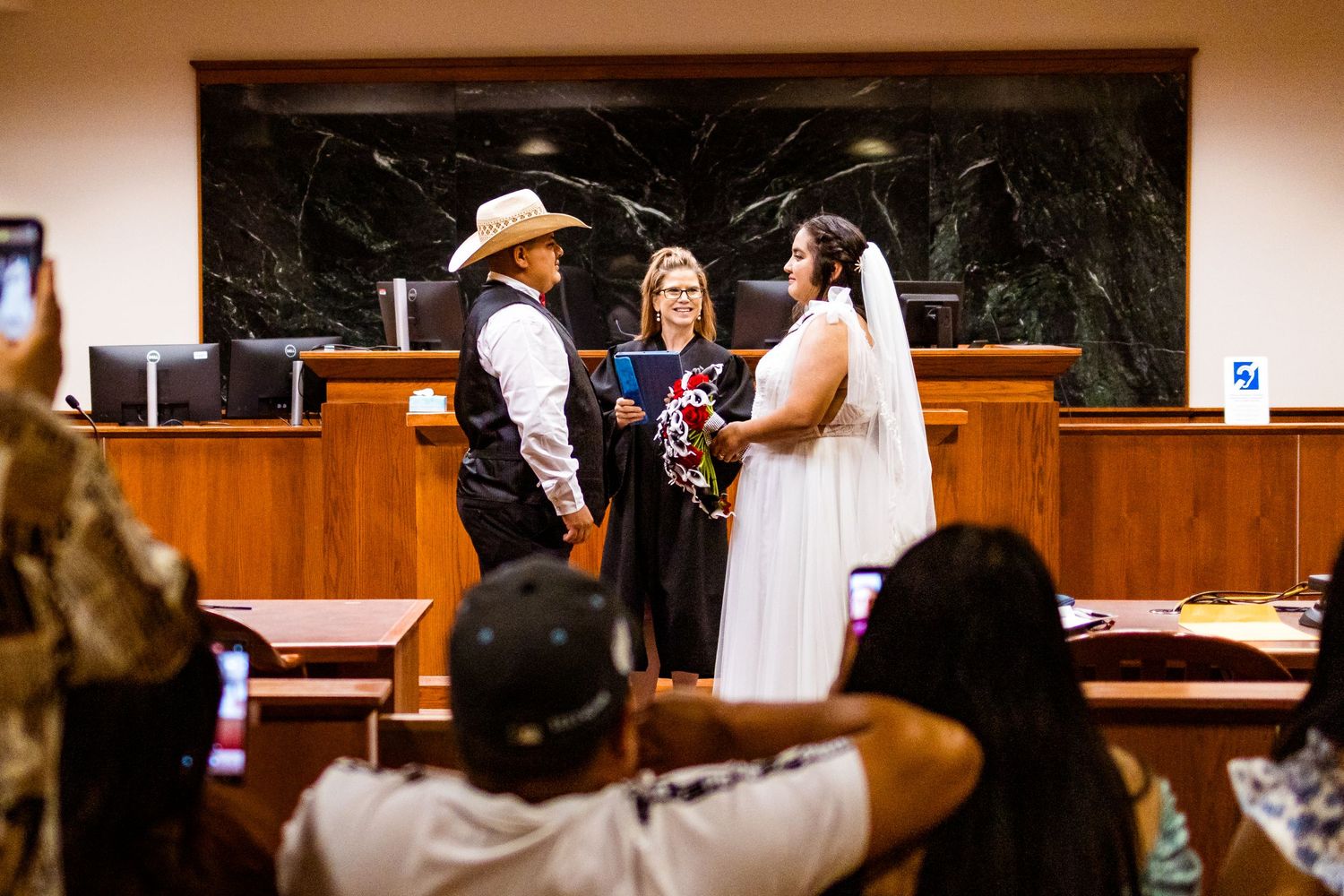 A couple stands at a wooden altar during their wedding ceremony in a traditional church setting.