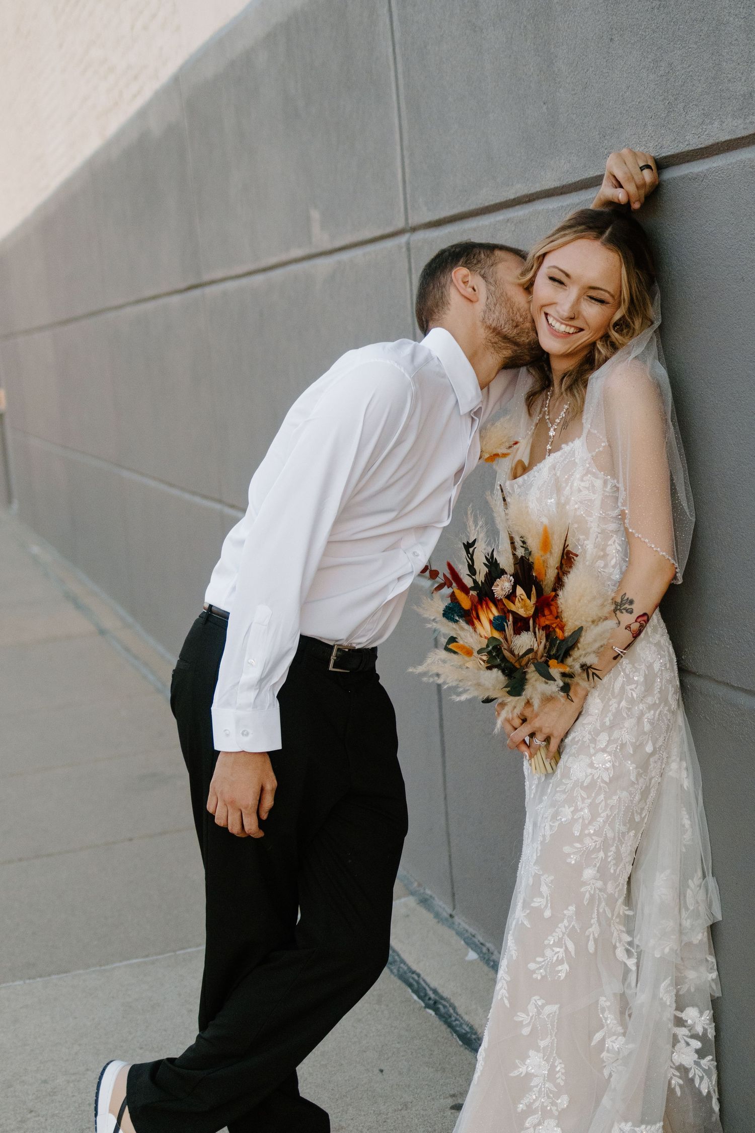 A couple in wedding attire shares romantic moments against a gray wall in a series of candid photos.