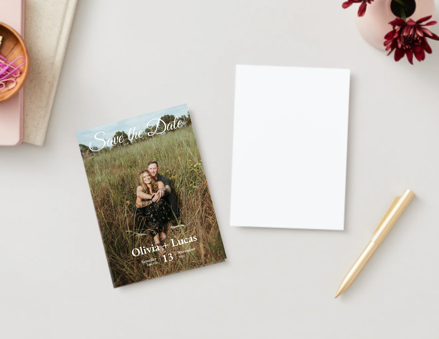 Collection of photo prints and floral decorations arranged on a white surface with pencils and paper clips.
