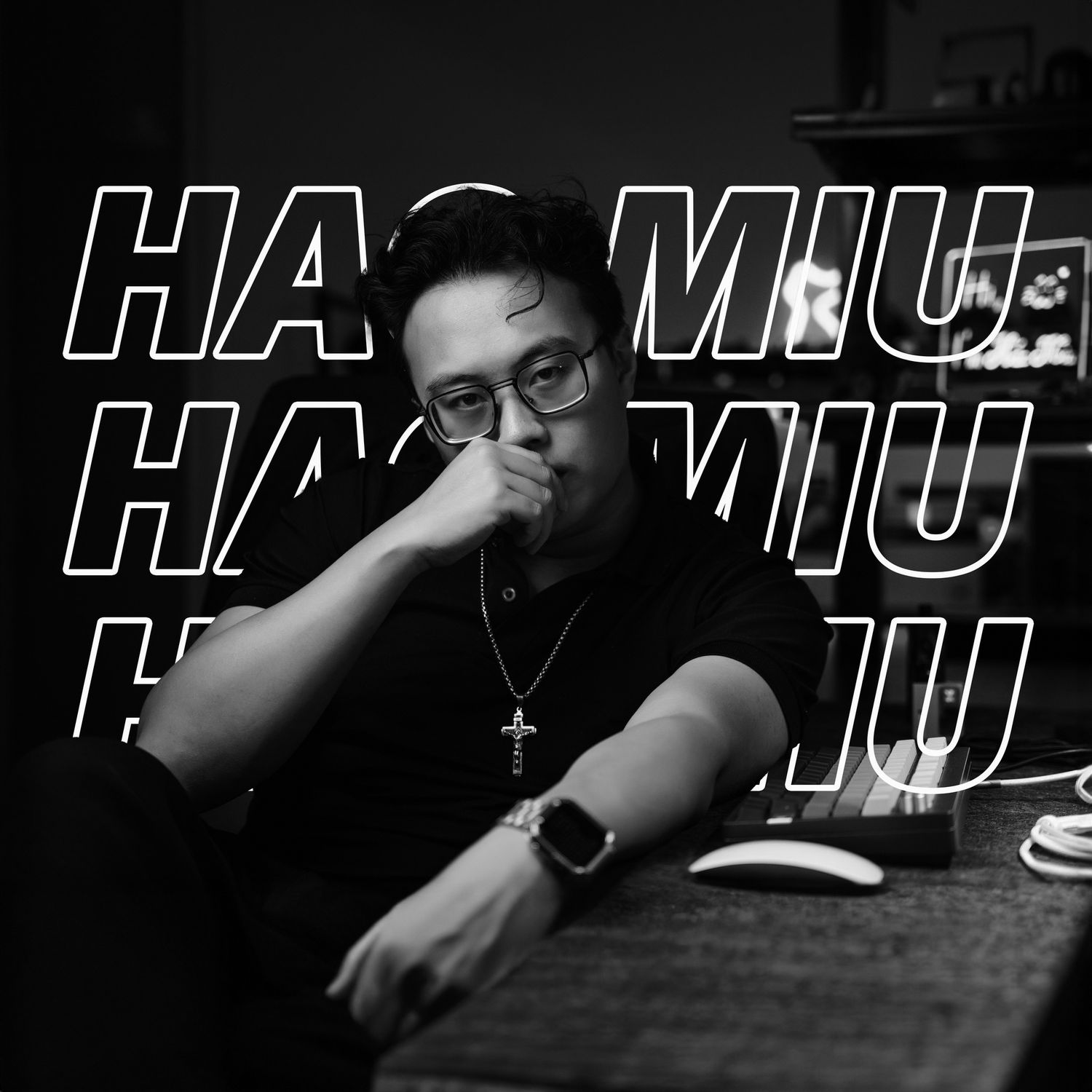 A person in glasses wearing dark clothing sits at a table with text overlaid reading 