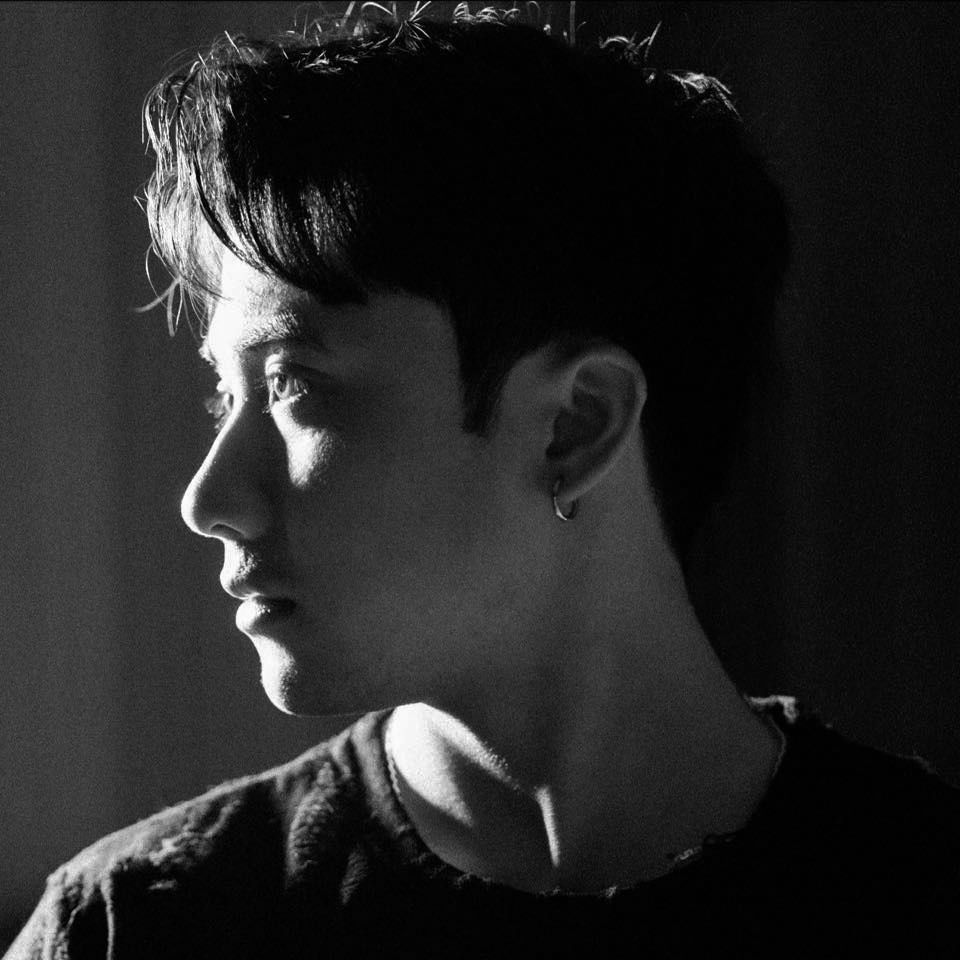 Dramatic black and white side profile portrait with stark lighting highlighting facial features against dark background.
