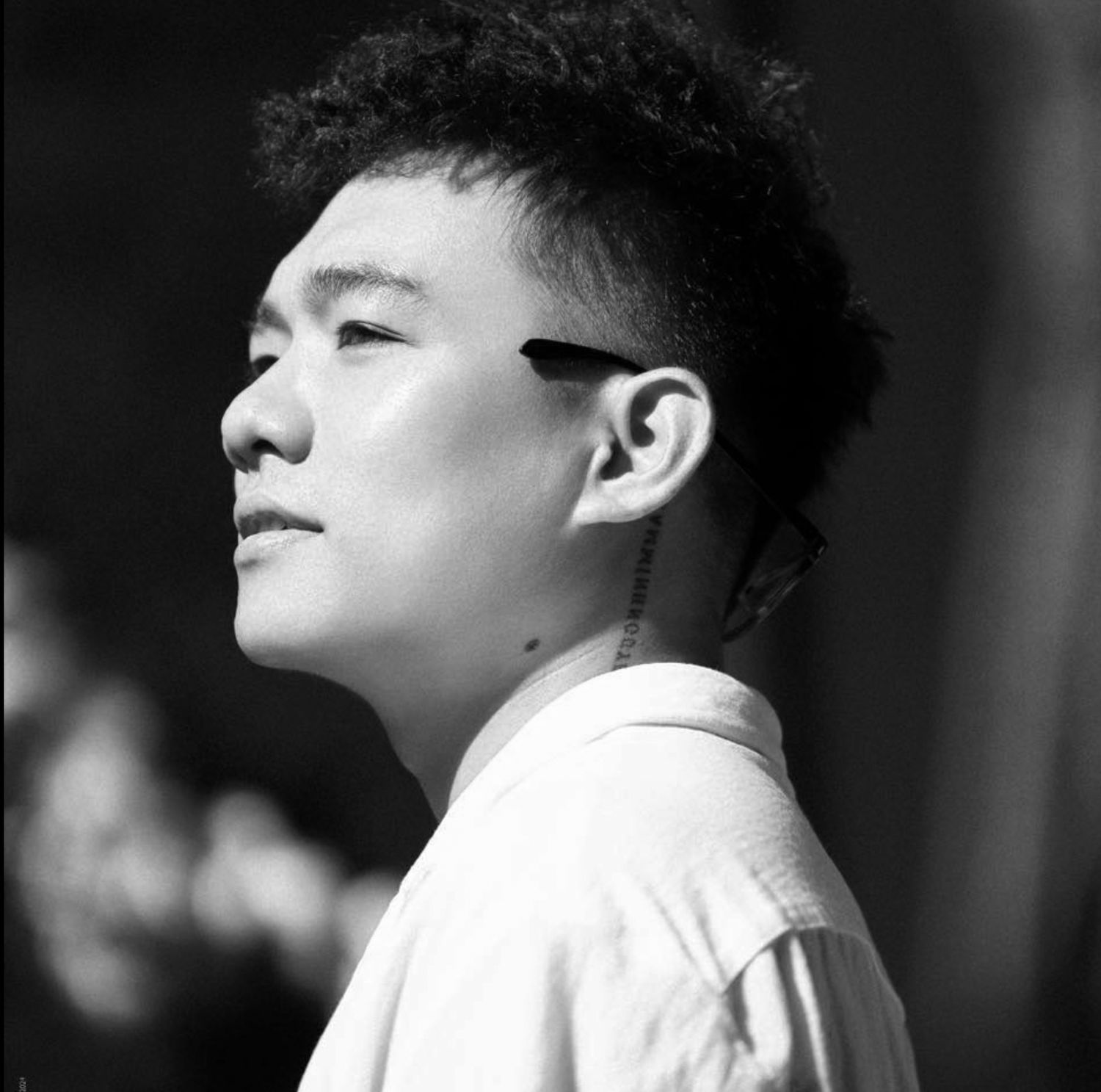 Black and white profile portrait of a person in a white shirt with eyes closed and short dark hair in contemplative pose.