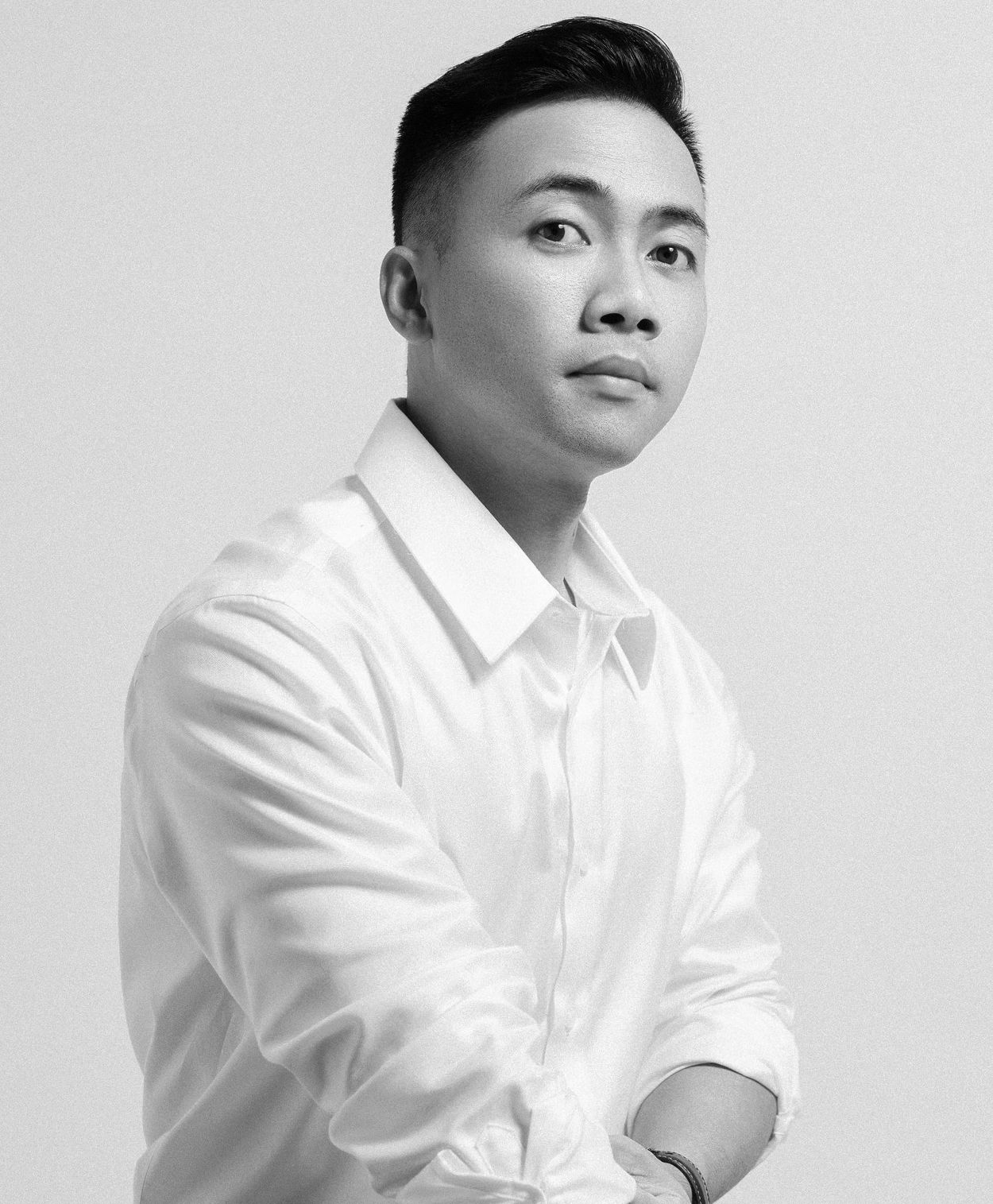 Black and white portrait of a person in a crisp white button-down shirt looking confidently to the side.