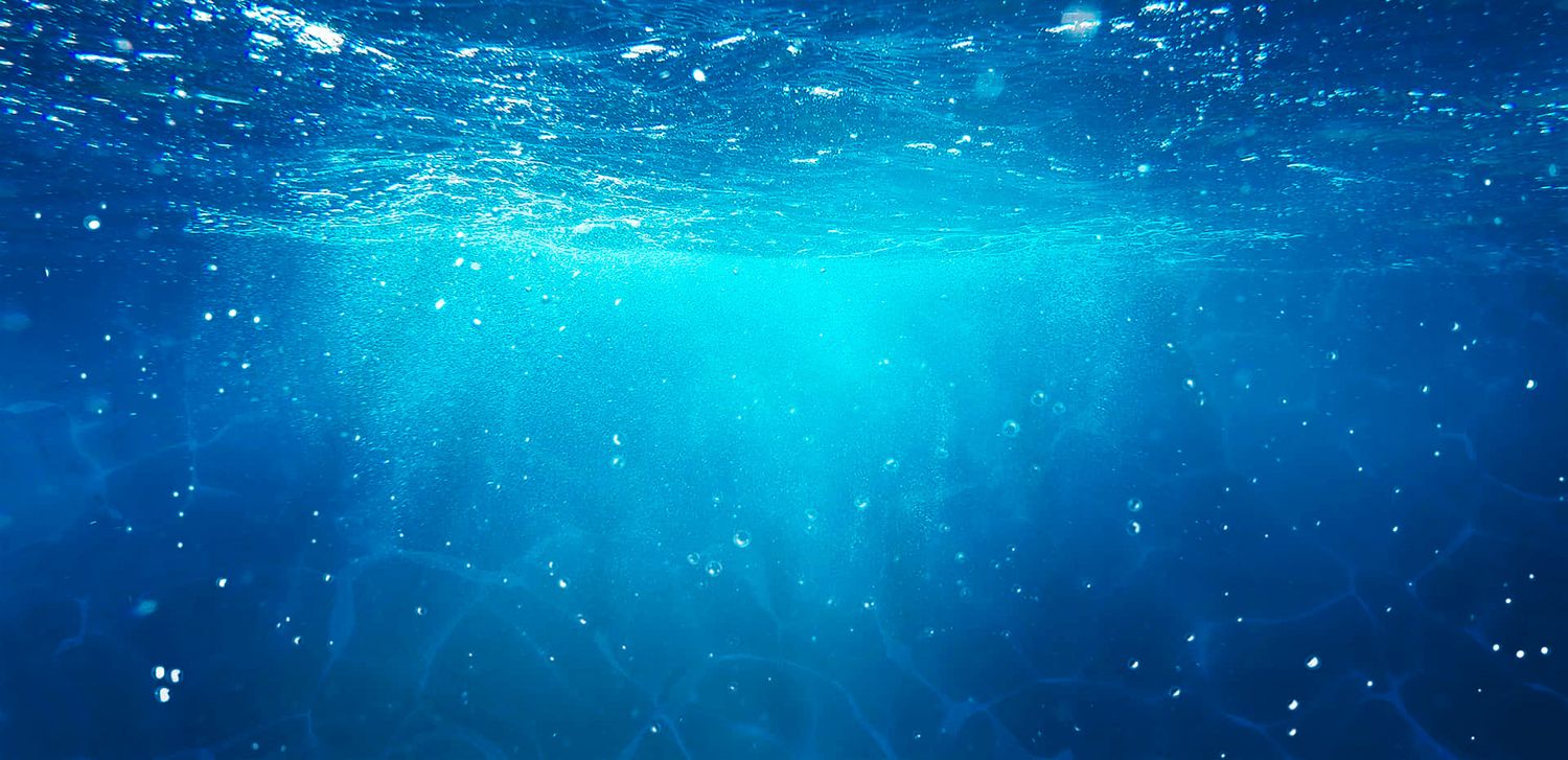 Underwater scene with sunlight filtering through crystal clear blue waters.
