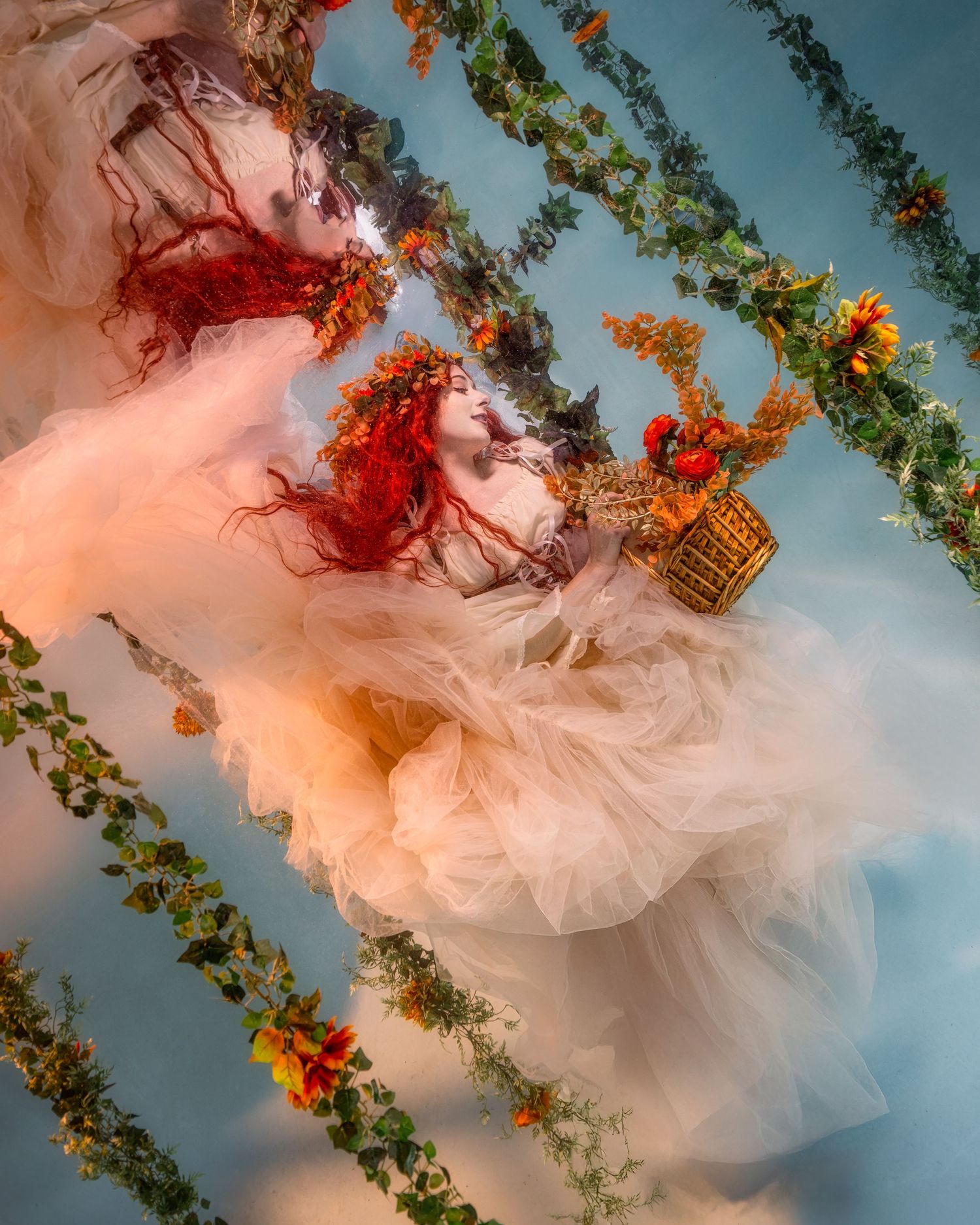 Ethereal figure in flowing white dress suspended among floral vines against blue sky in dreamy artistic portrait.