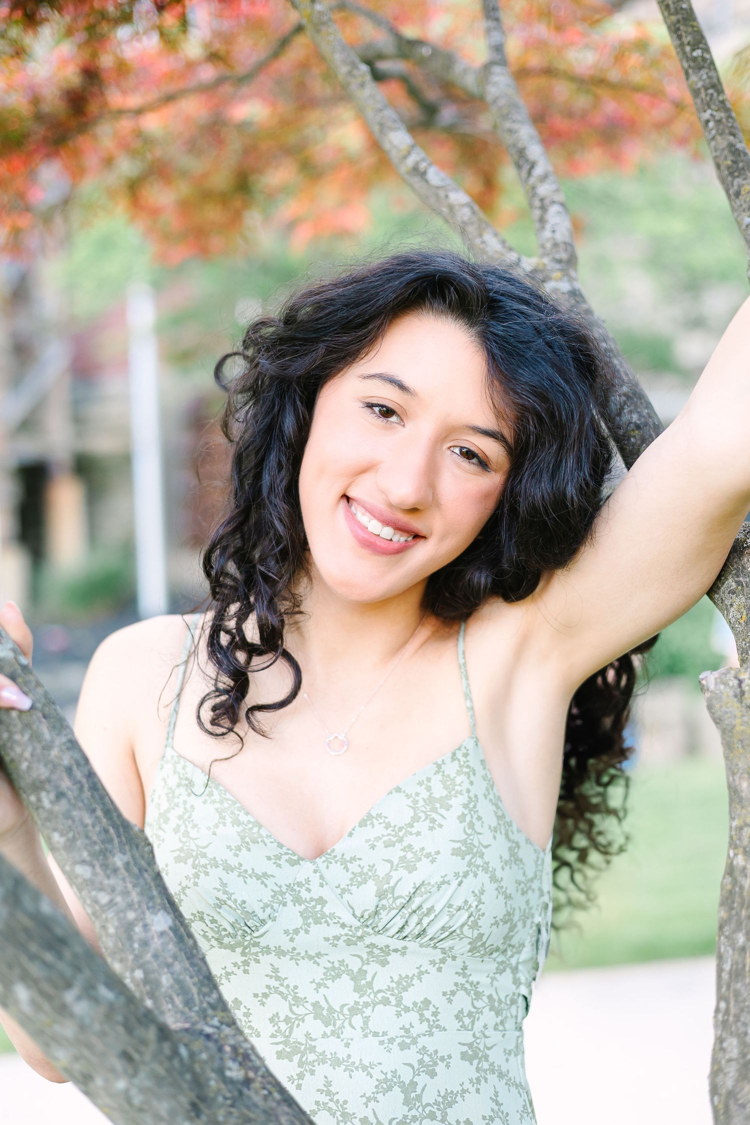 A joyful portrait outdoors with autumn foliage and tree branches framing the scene in soft natural lighting.