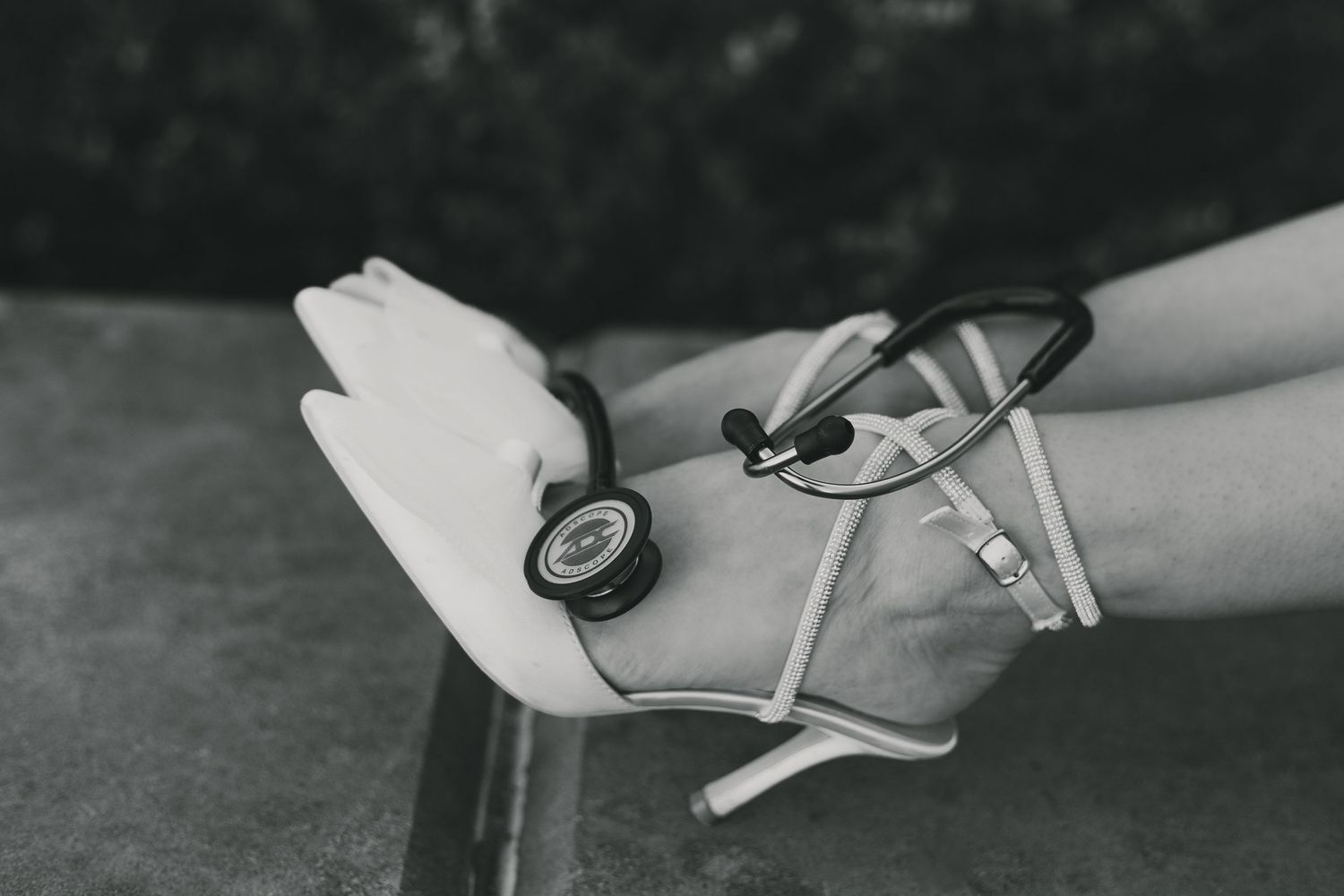 Black and white closeup of stethoscope being held against white background.