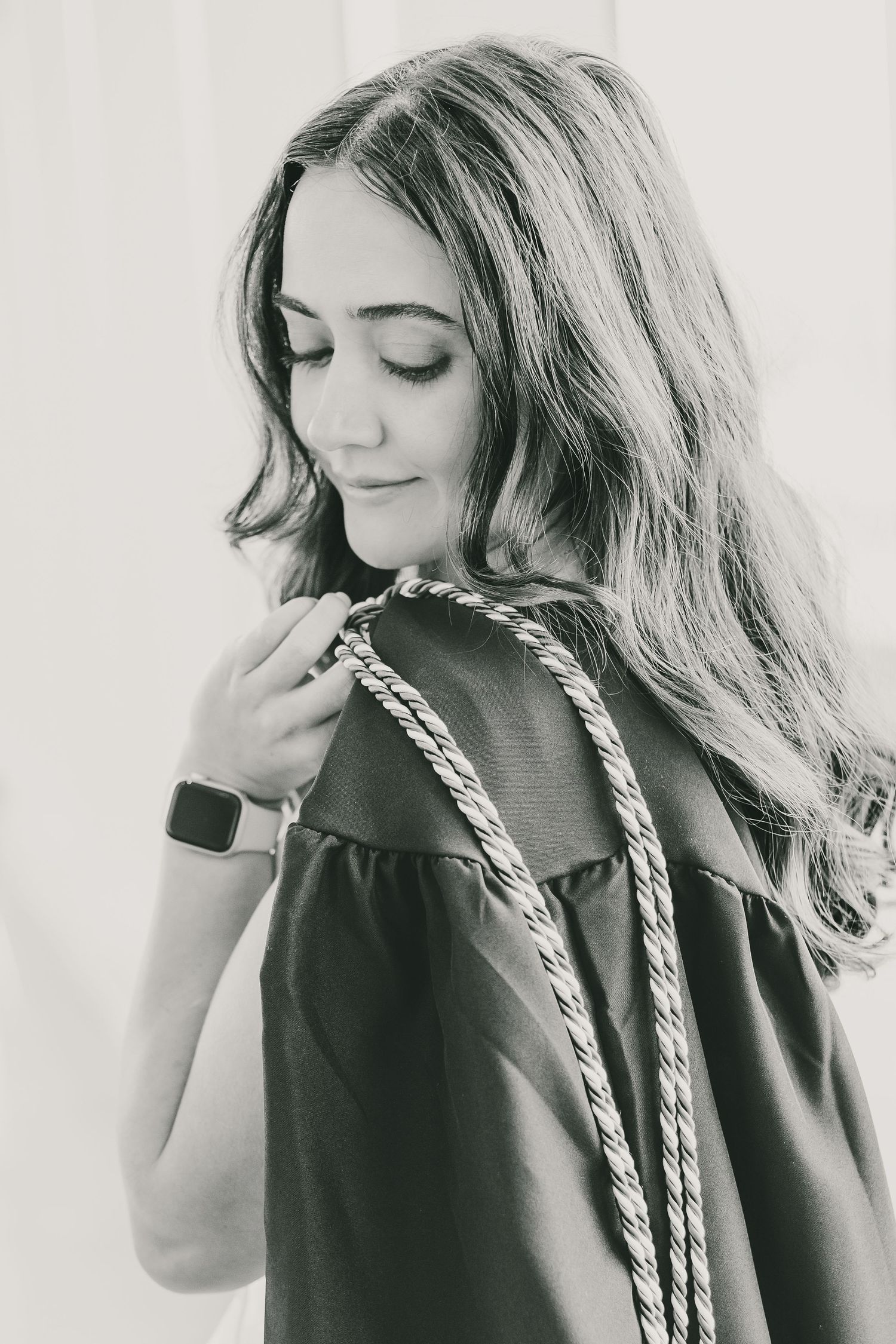 Close-up black and white portrait of a woman in a dark dress with wavy hair and smartwatch.