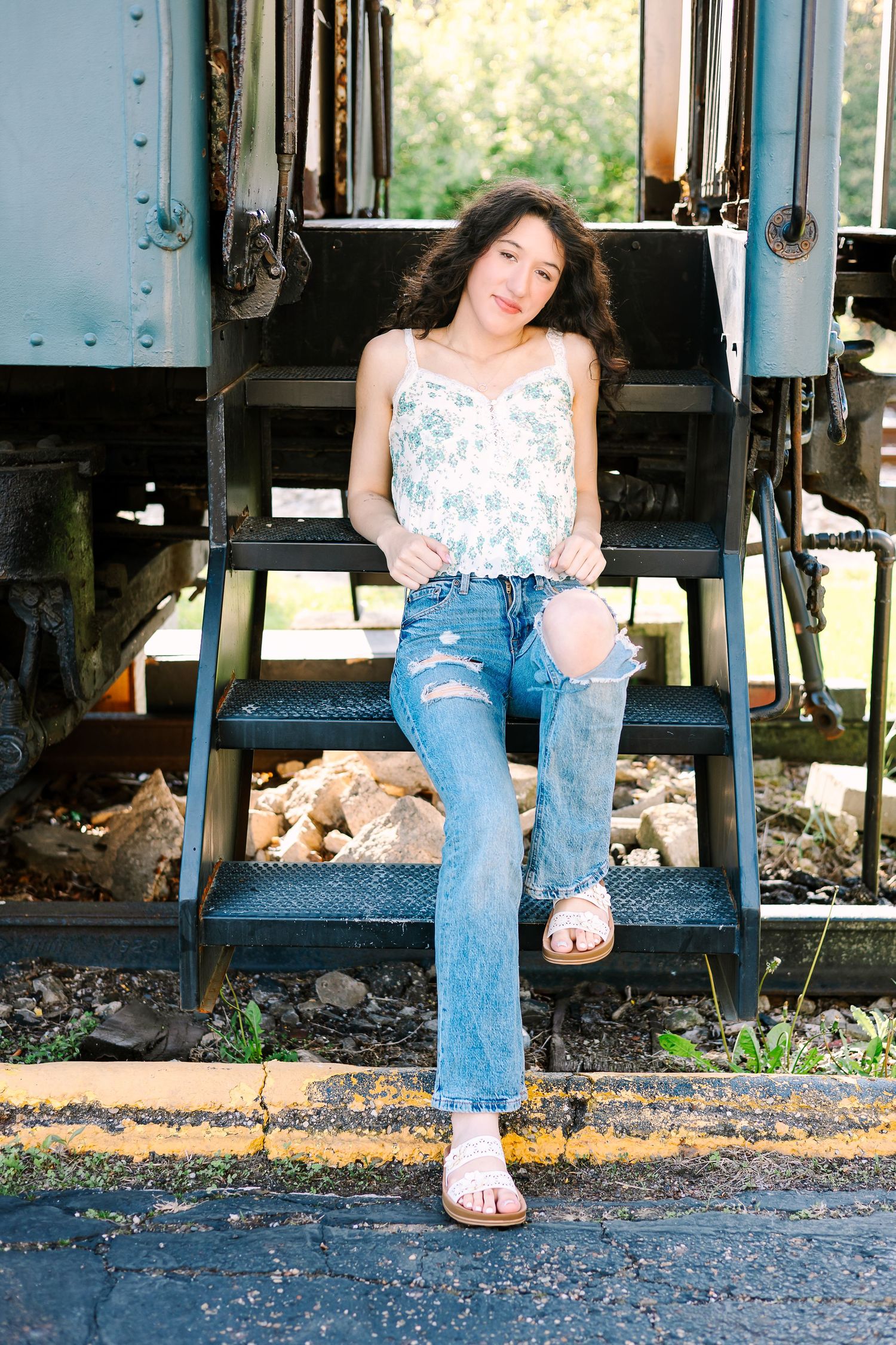 A person in ripped jeans and sandals sits casually on the steps of a train car, shown from different angles.