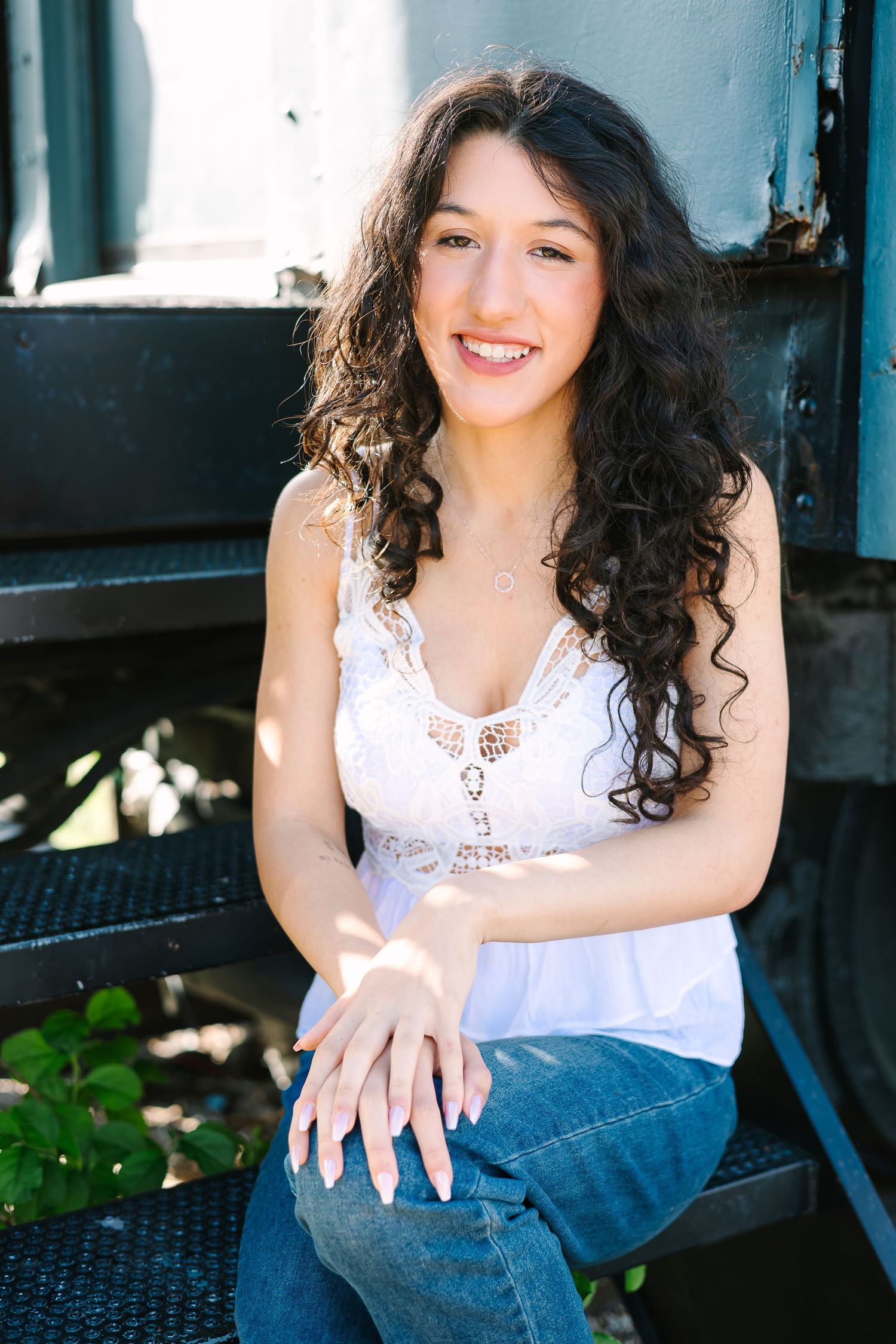 Series of casual portrait shots showing someone with dark curly hair in a white top sitting outdoors in natural lighting.