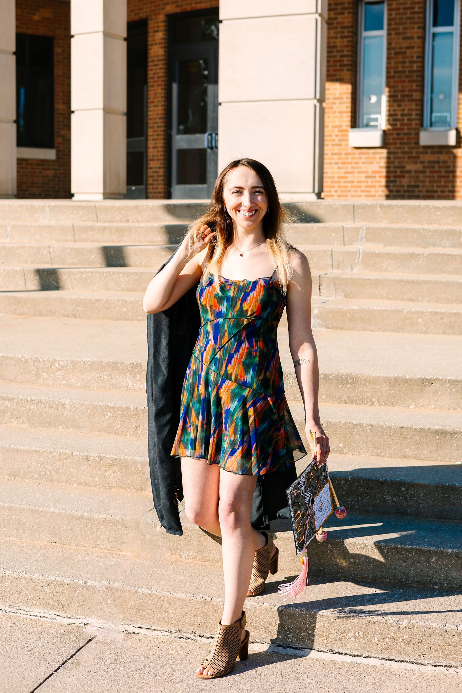 A colorful floral sundress is shown in a triptych sequence on stone steps outside a brick building in bright sunlight.