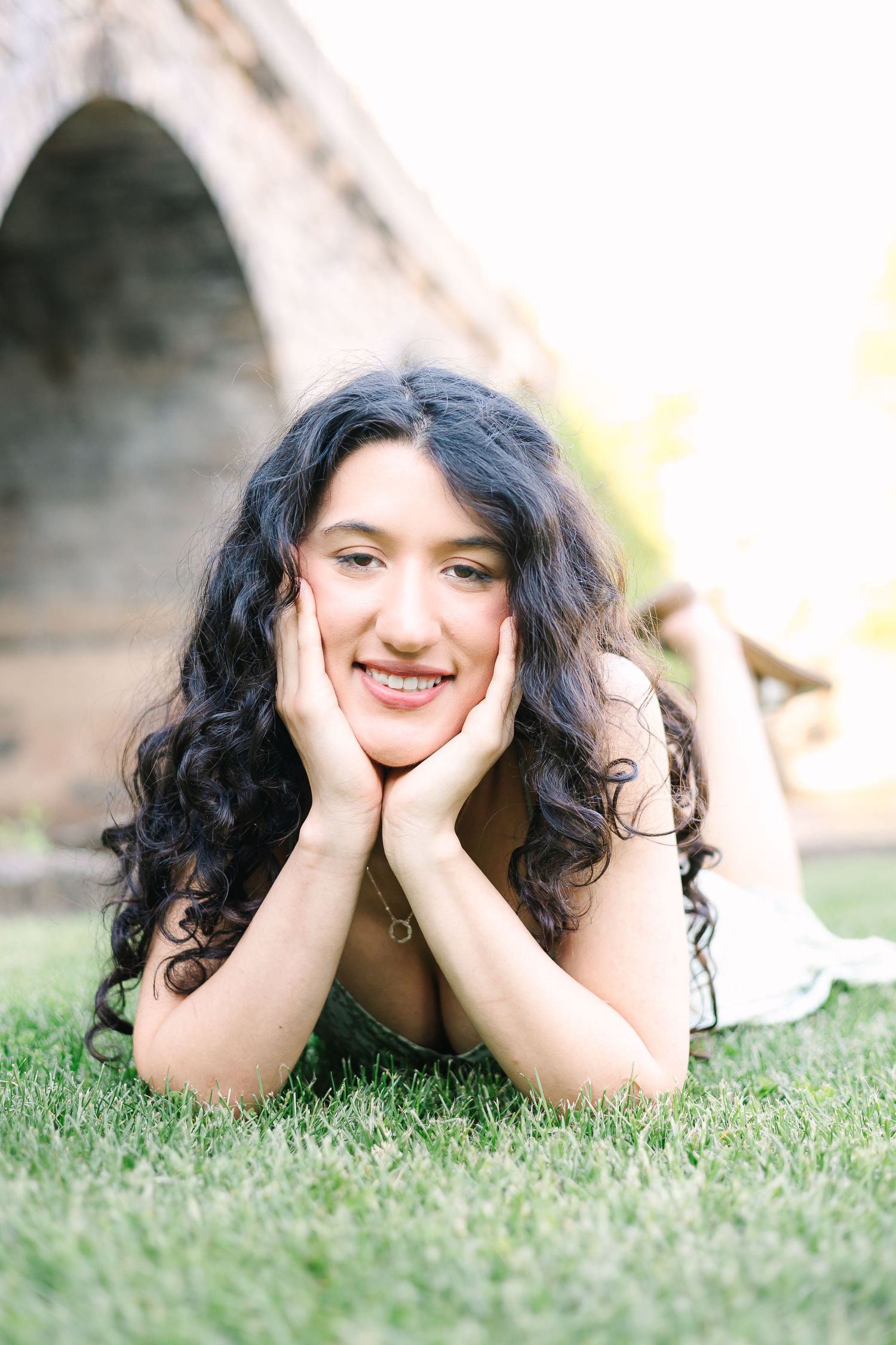 Three casual outdoor portrait shots of someone laying on grass with relaxed, joyful expressions.