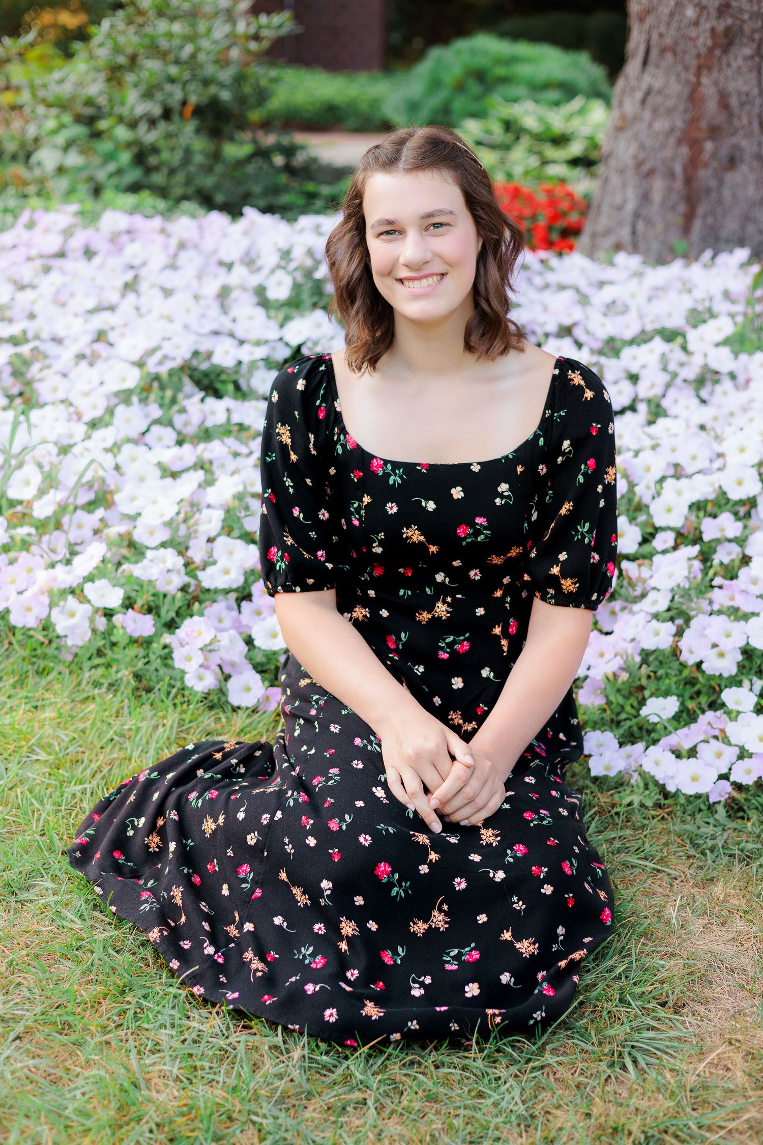 Black floral dress stands out against backdrop of white flowers in garden setting.