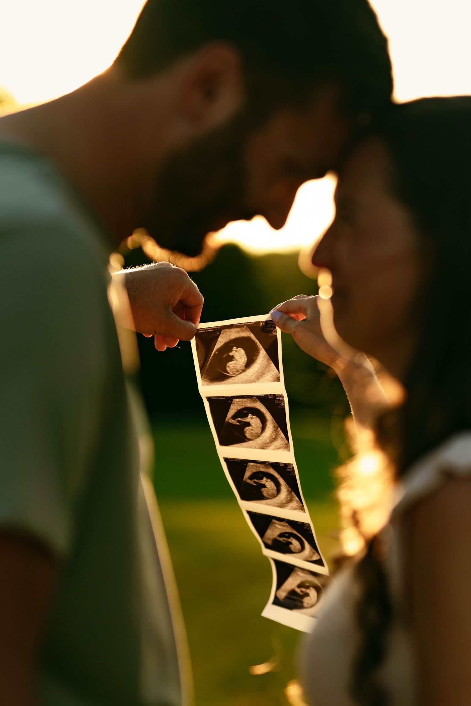Ultrasound photos held up against golden sunset light.