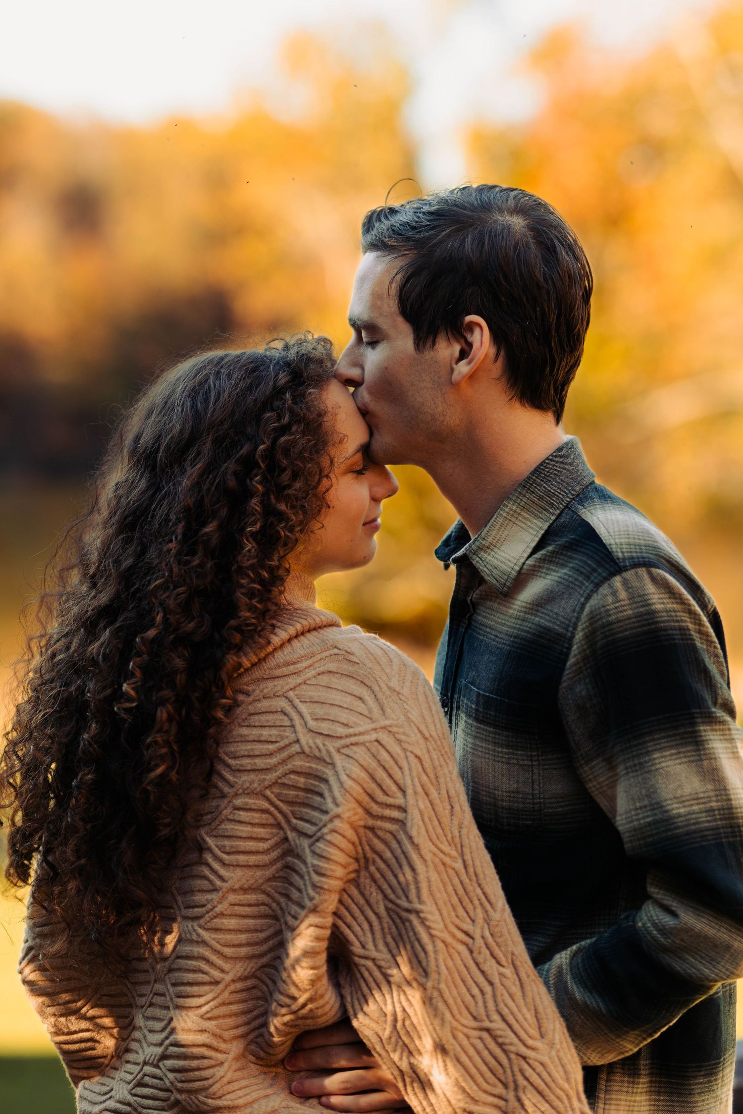 A romantic couple embraces in a series of intimate poses against a warm autumn backdrop.