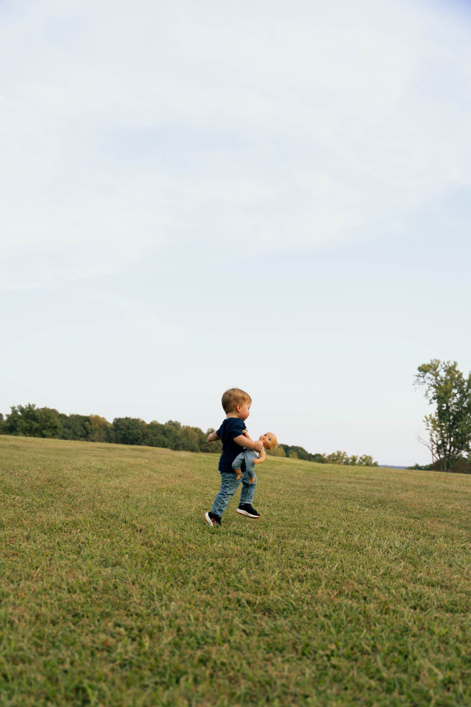 Small child running freely across a grassy hilltop.