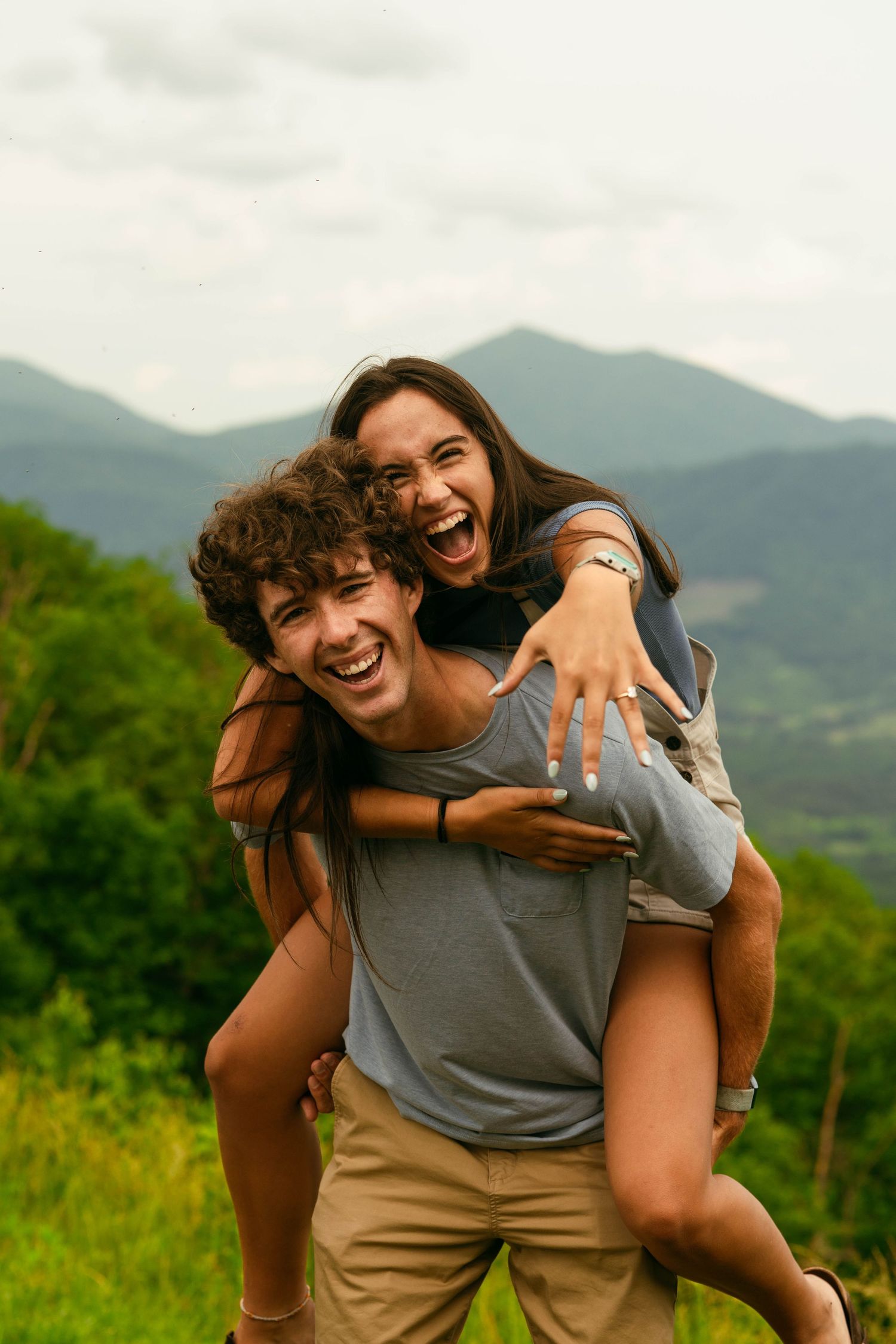Playful piggyback ride moment captured against a scenic mountain backdrop on a sunny day.