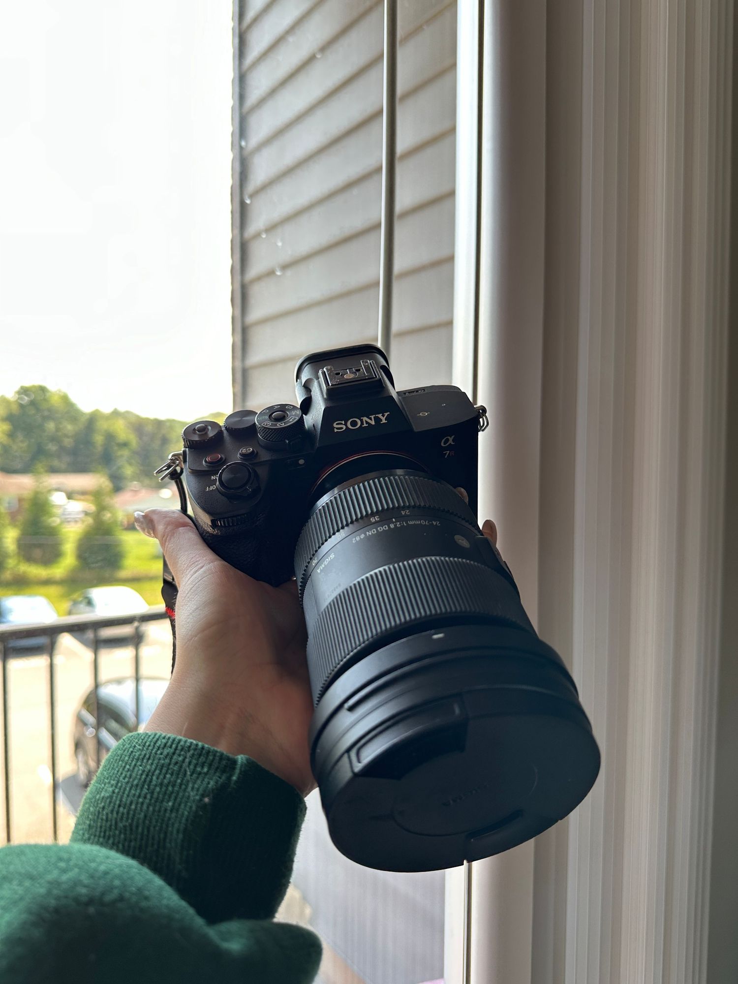 Multiple shots of hands holding a Sony camera against window blinds.