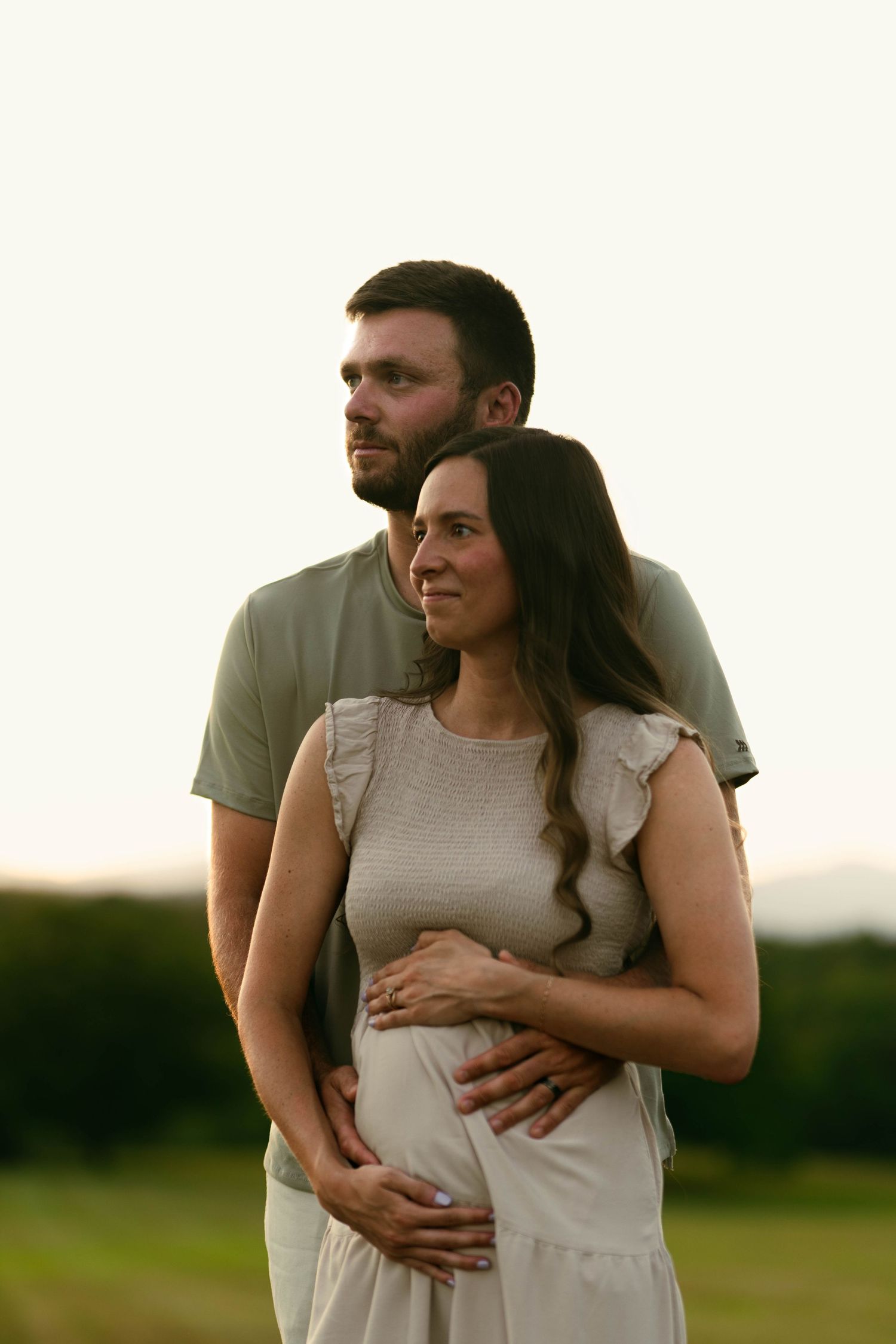 A maternity photoshoot sequence showing a couple embracing outdoors at sunset.