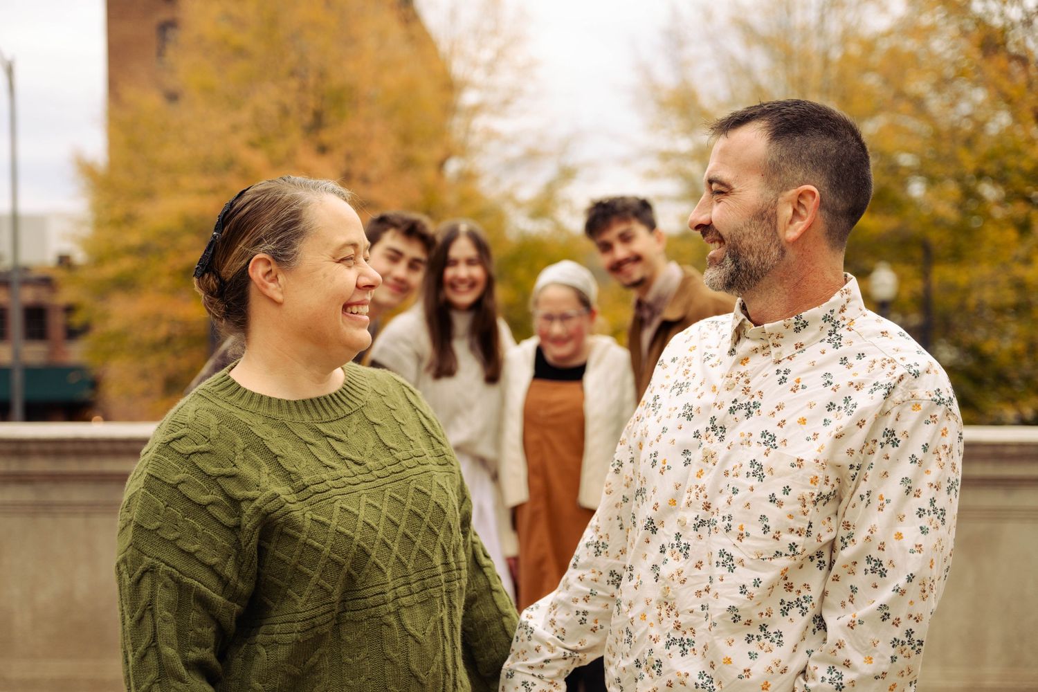 Group laughing together outdoors during autumn family photo session.