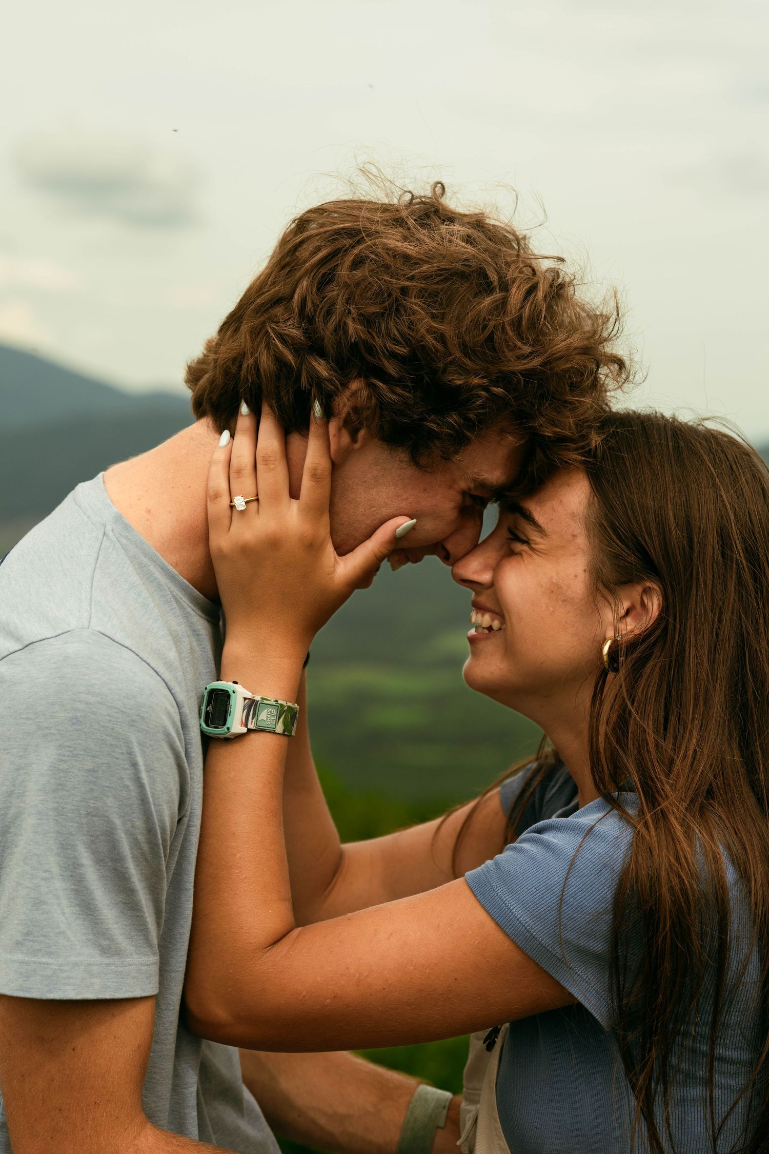 A young couple embracing affectionately in a scenic outdoor setting.