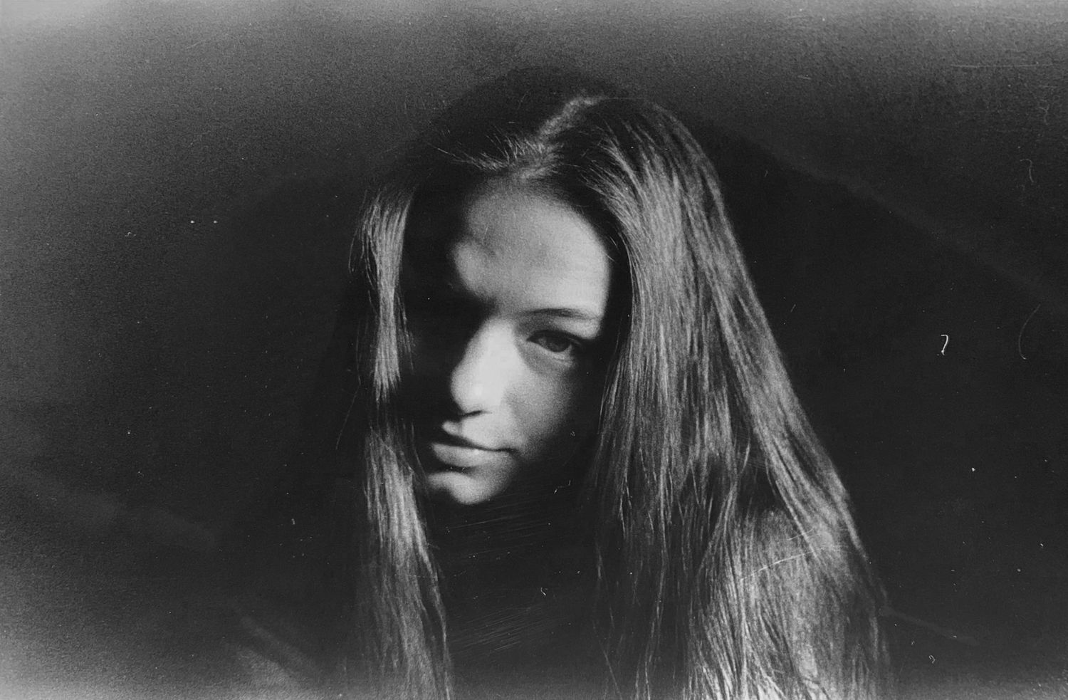 The image shows a close-up portrait of a young woman with long, dark hair looking directly at the camera.