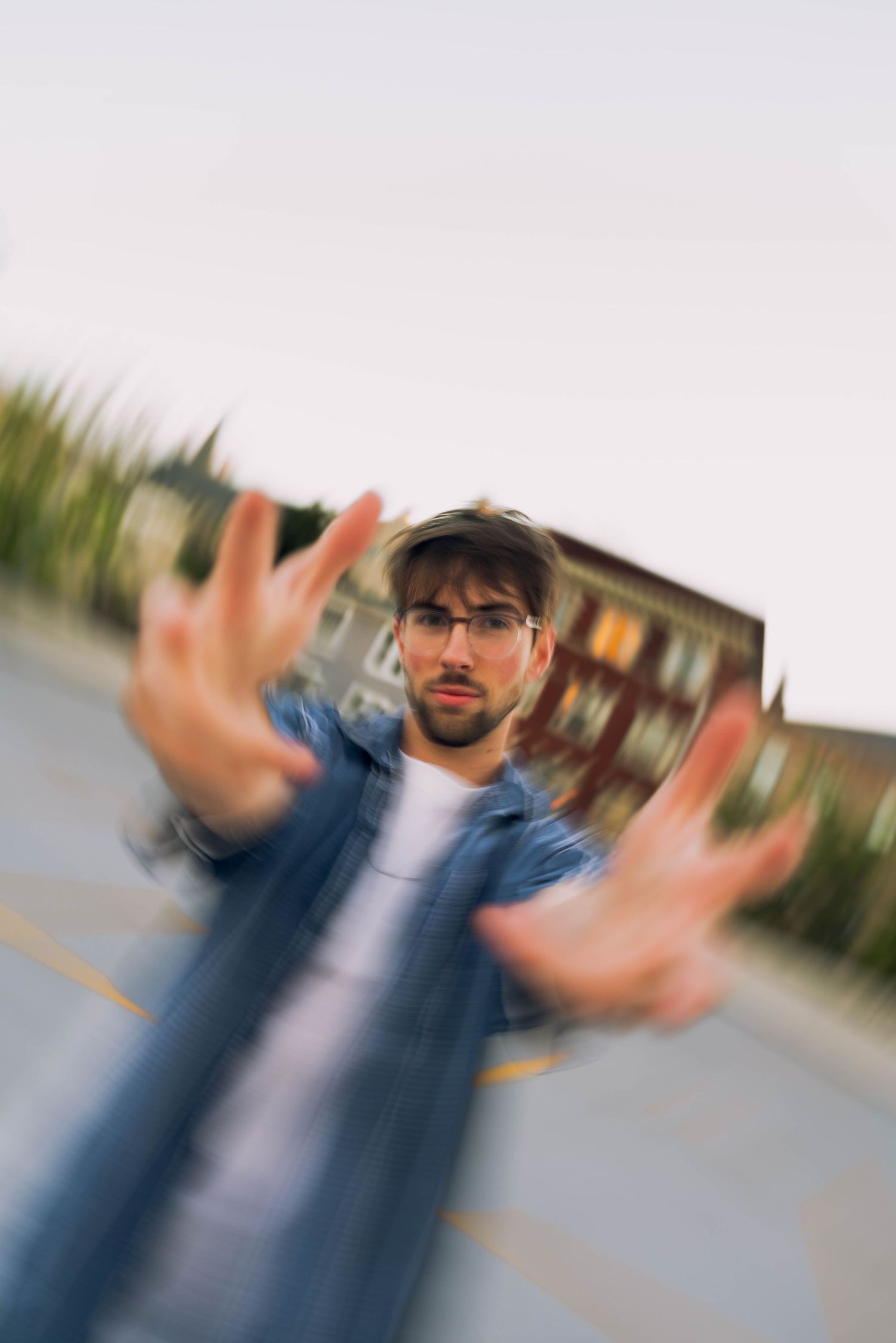 A blurred image shows a man with facial hair wearing a denim jacket gesturing with his hands in the foreground.