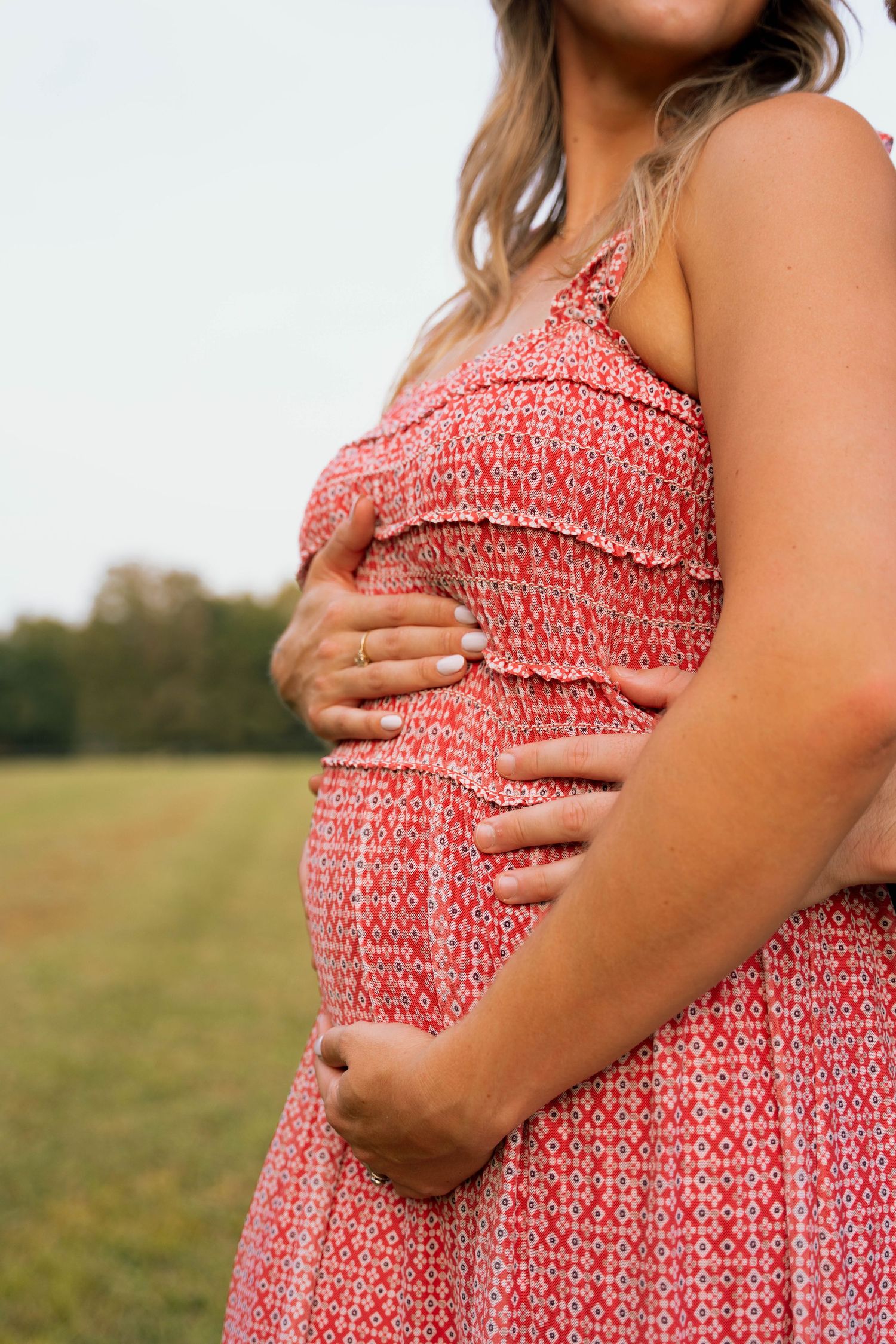 Close-up of a coral patterned maternity dress showing a growing baby bump.