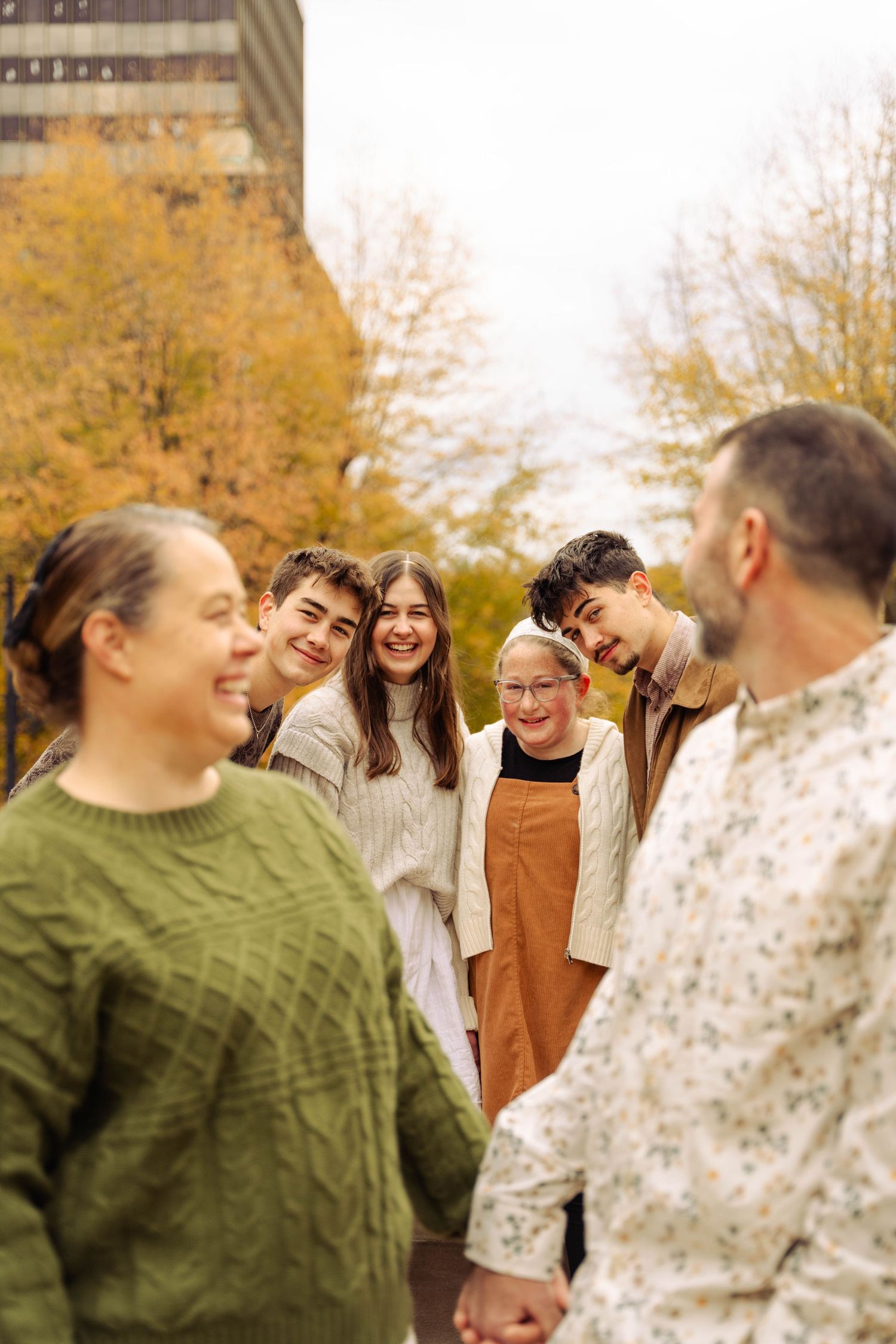 A group of people standing together in an outdoor setting with fall foliage in the background.