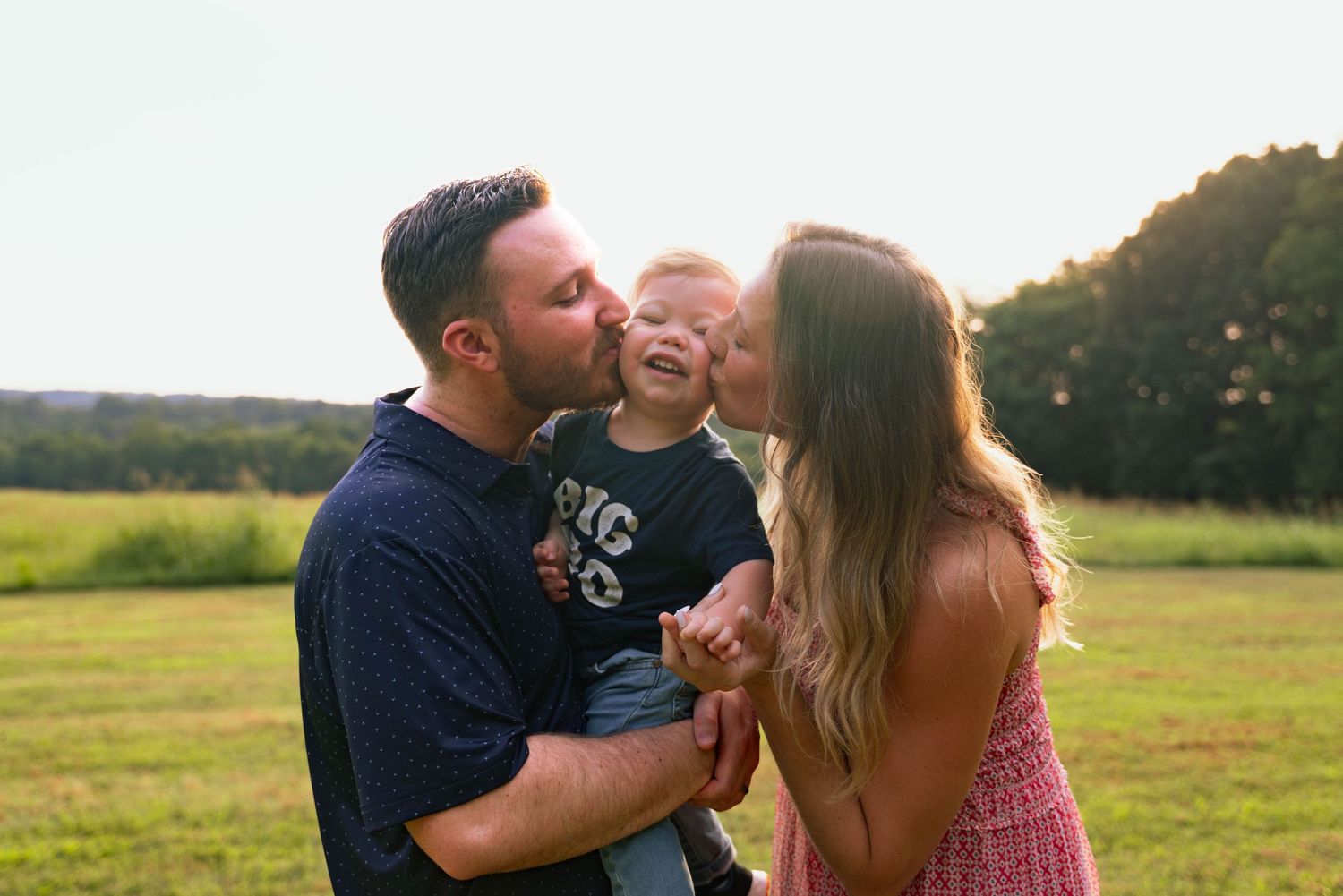 Family sharing affectionate moment in outdoor field setting.