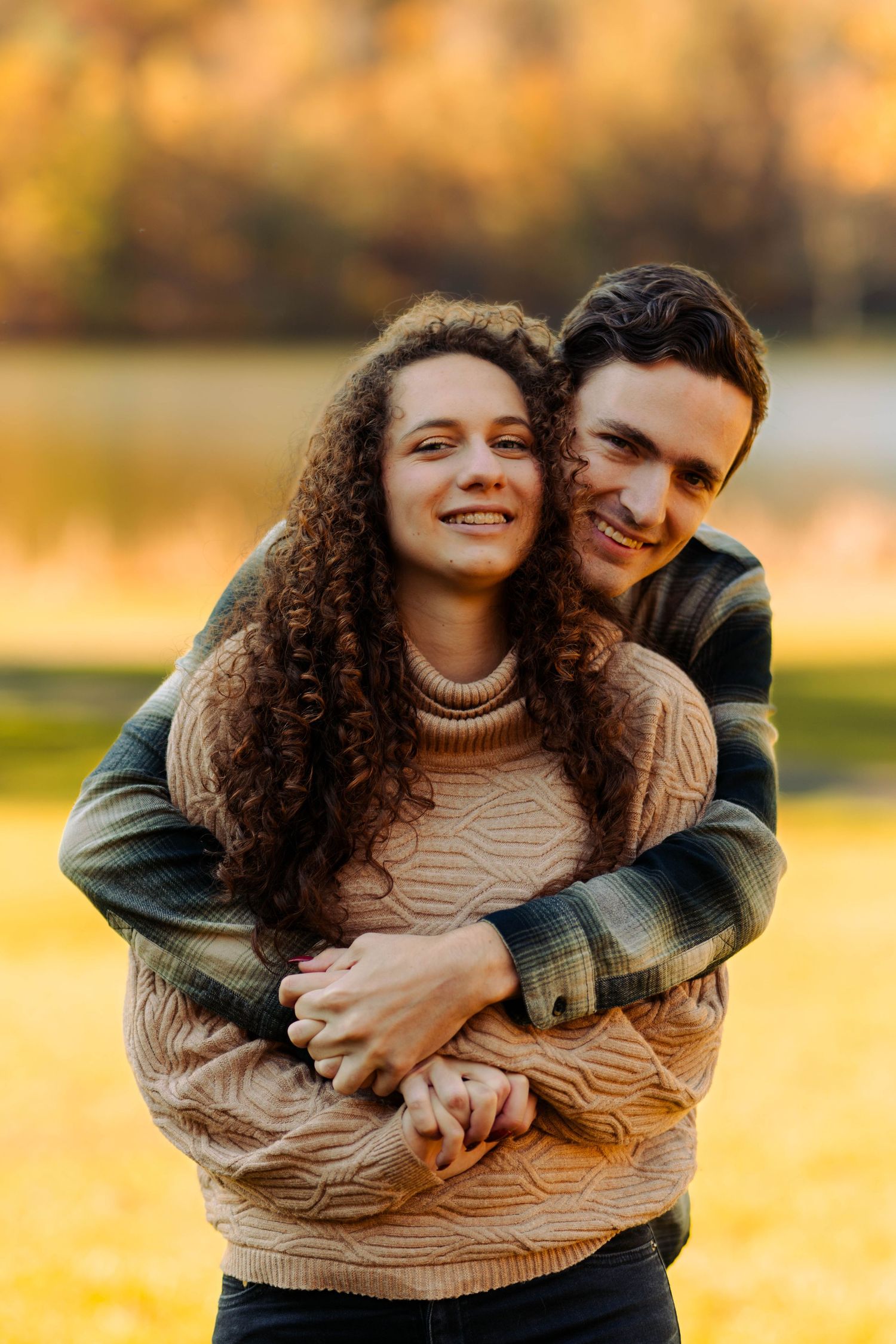 A couple shares a tender moment while embracing outdoors during golden hour.