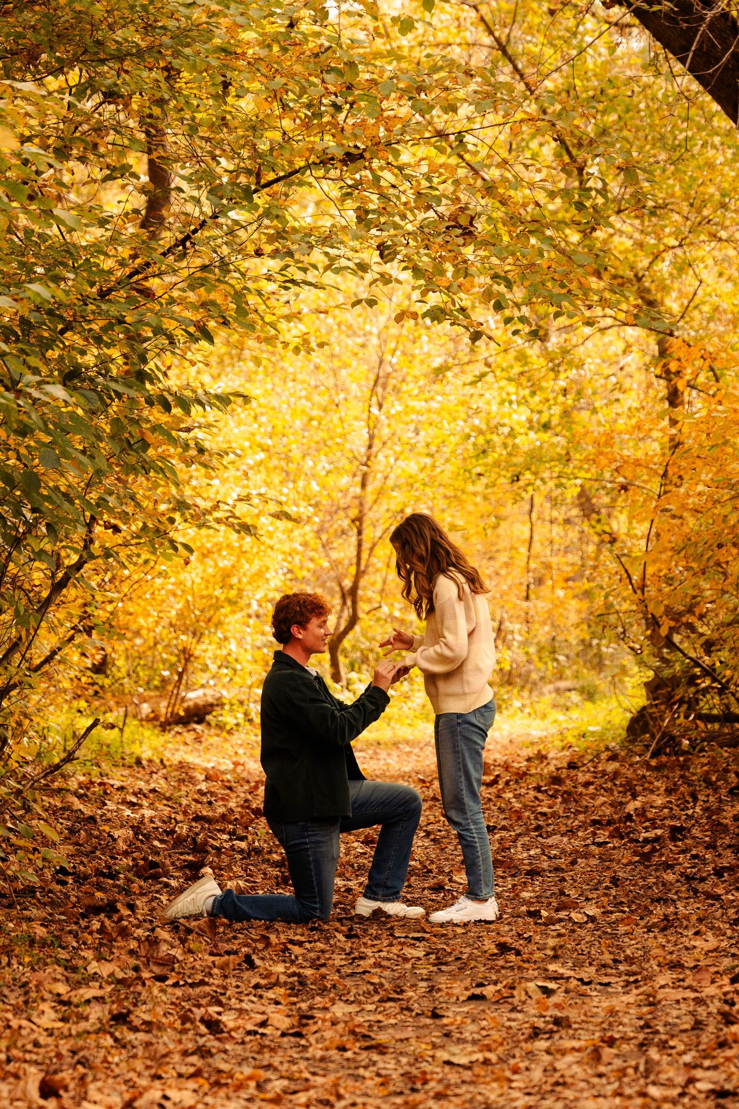 Romantic autumn proposal scene with golden leaves creating a magical backdrop.