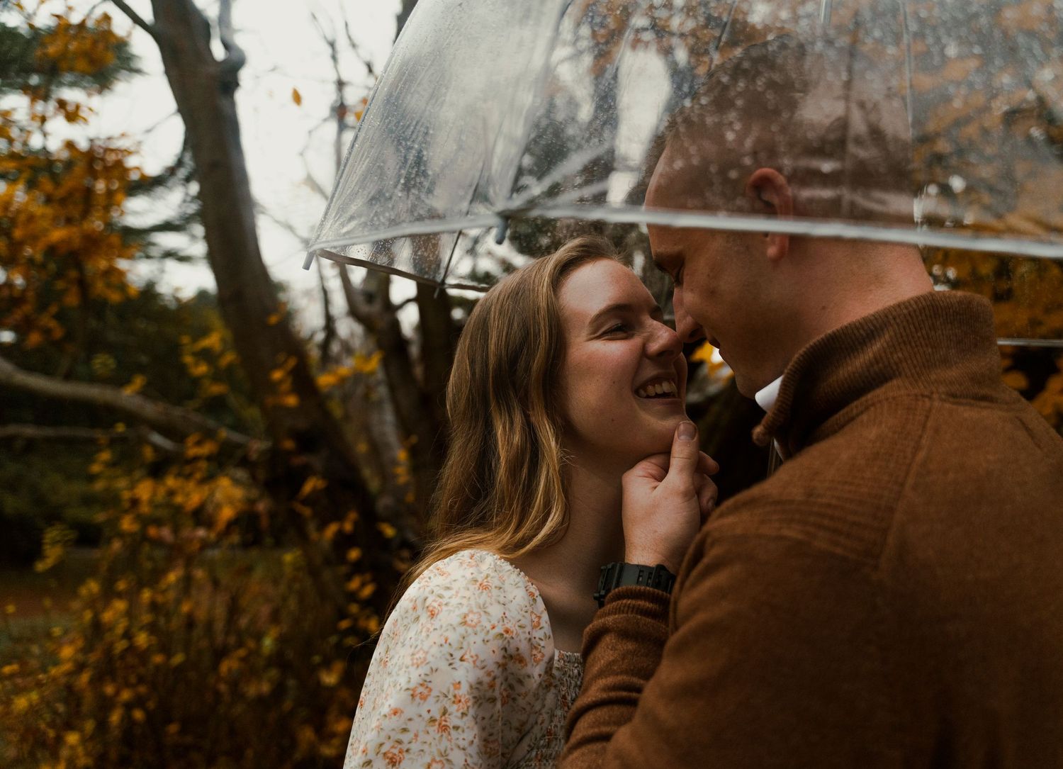 Intimate couple sharing tender moments in a fall setting with warm autumn colors.