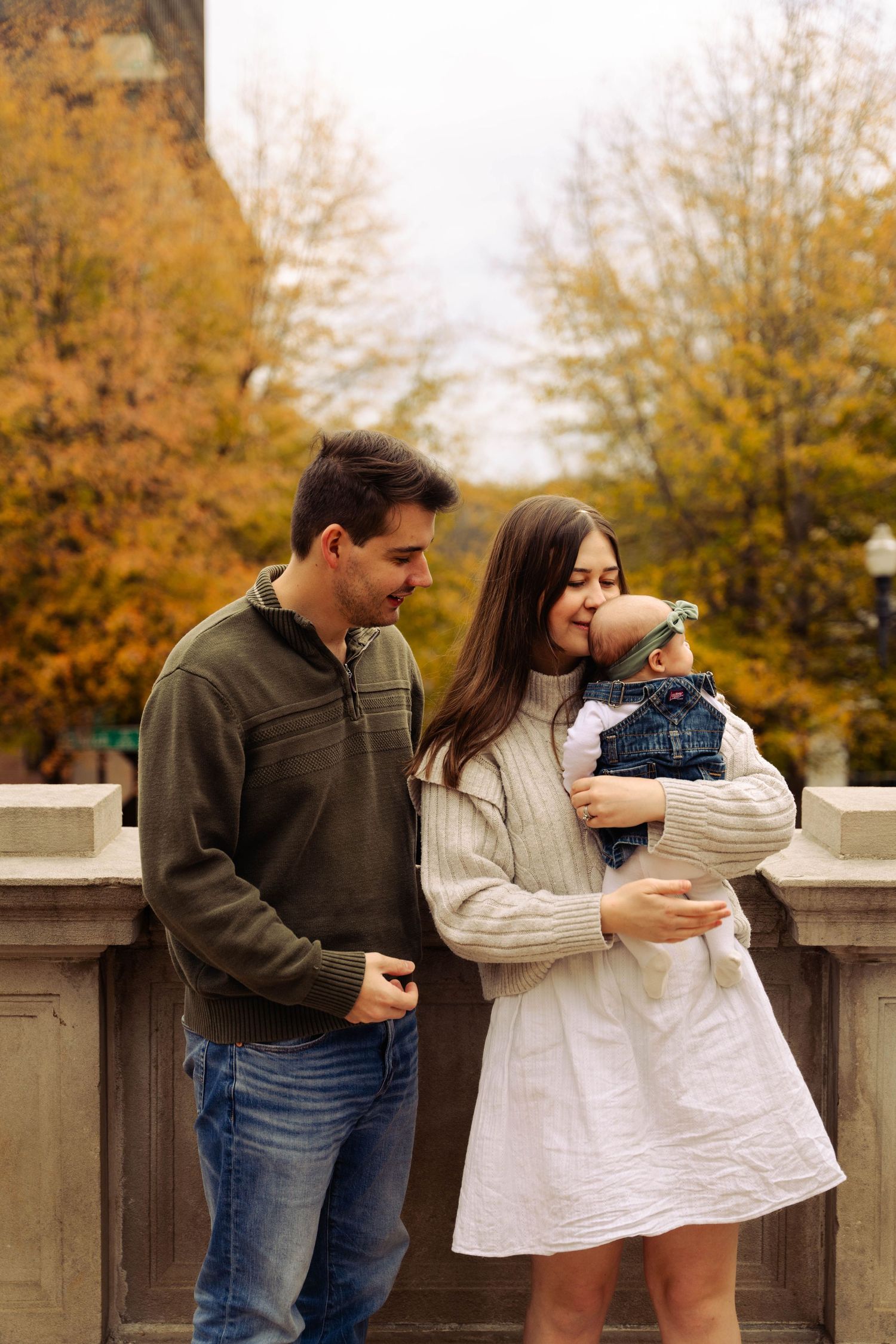 Tender family moment captured during autumn with golden foliage in background.