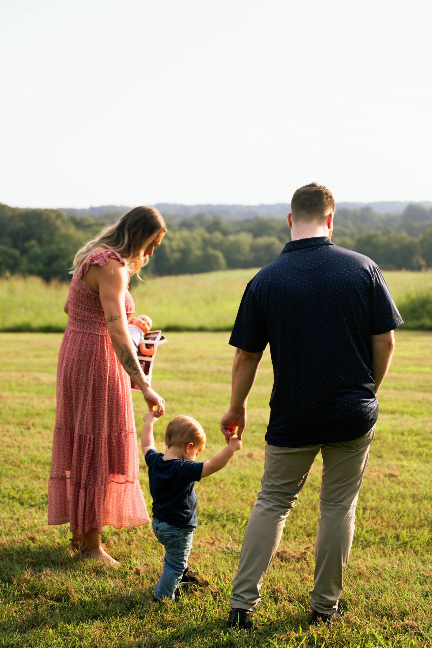 Family walking together in a sunny meadow during golden hour.