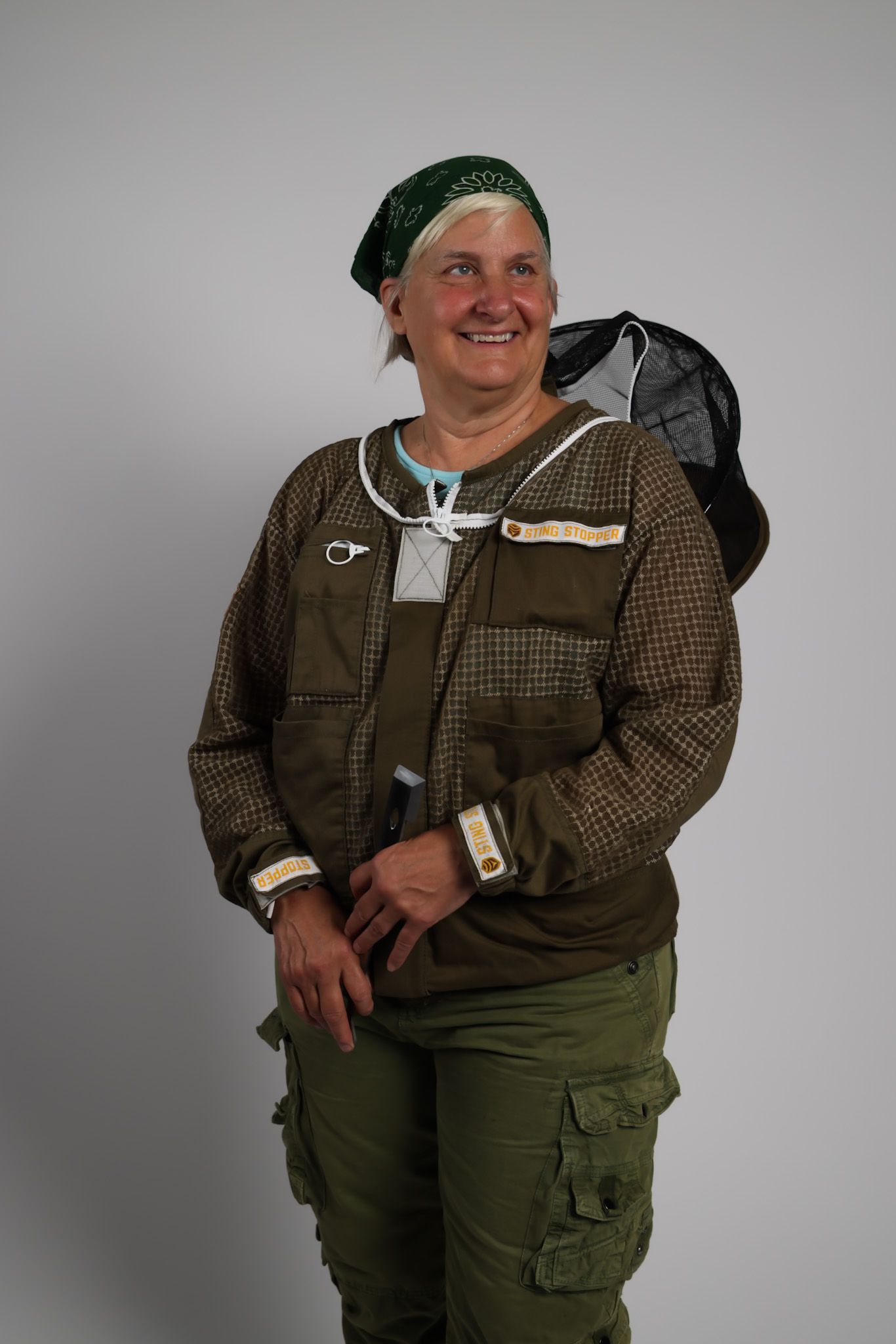 Person in hunting attire and bandana striking various playful poses against grey backdrop.