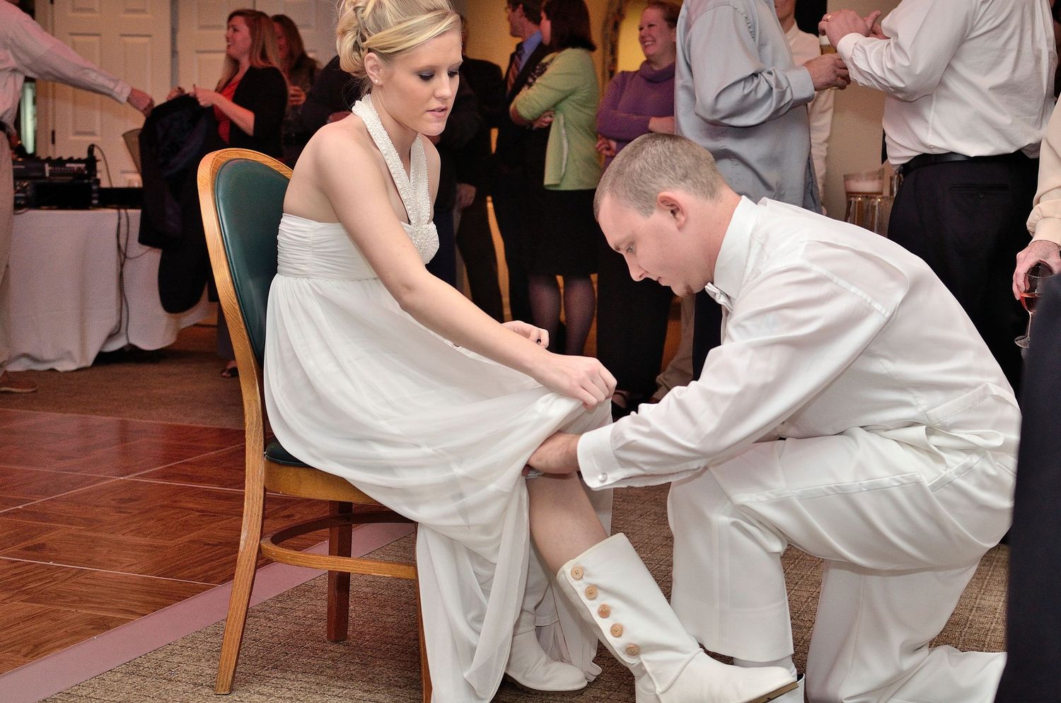 Groom kneeling to put on bride's shoe during wedding reception in Bristol TN/VA by MGE Photography