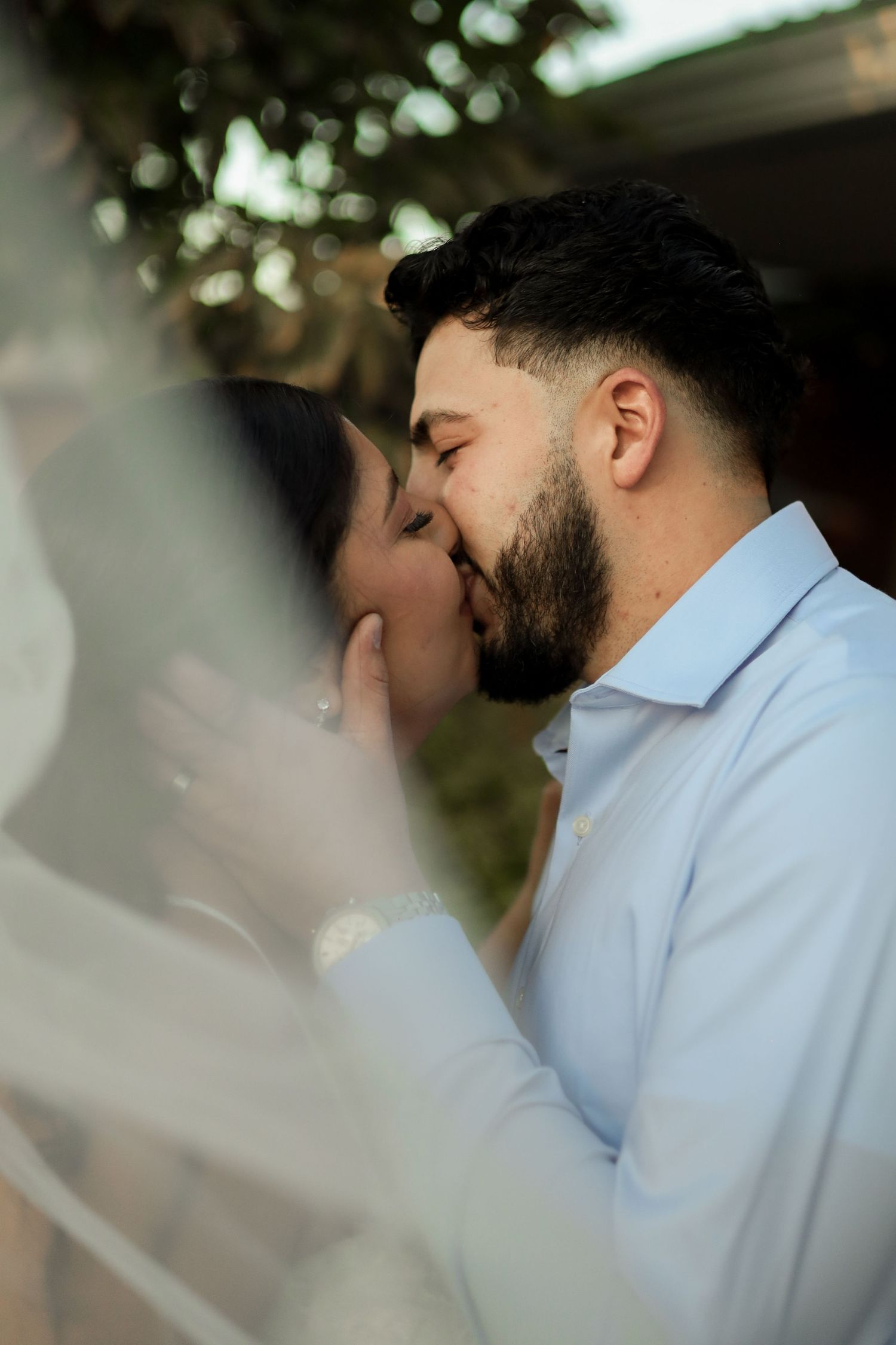 A romantic kiss shared between a couple on their wedding day with dreamy bokeh lighting effects.