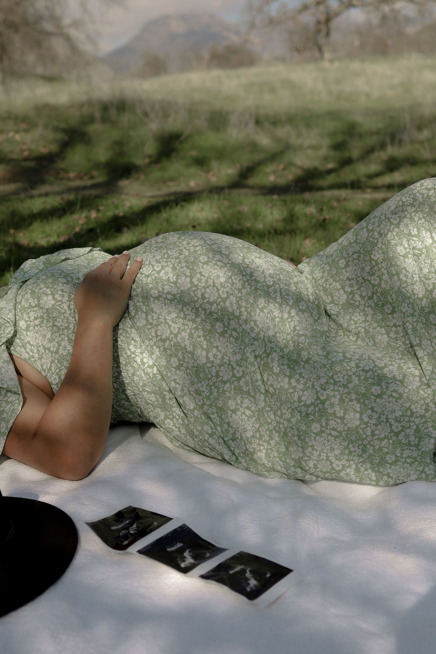 Artistic pregnancy announcement with sonogram photo placed on textured stone surface.