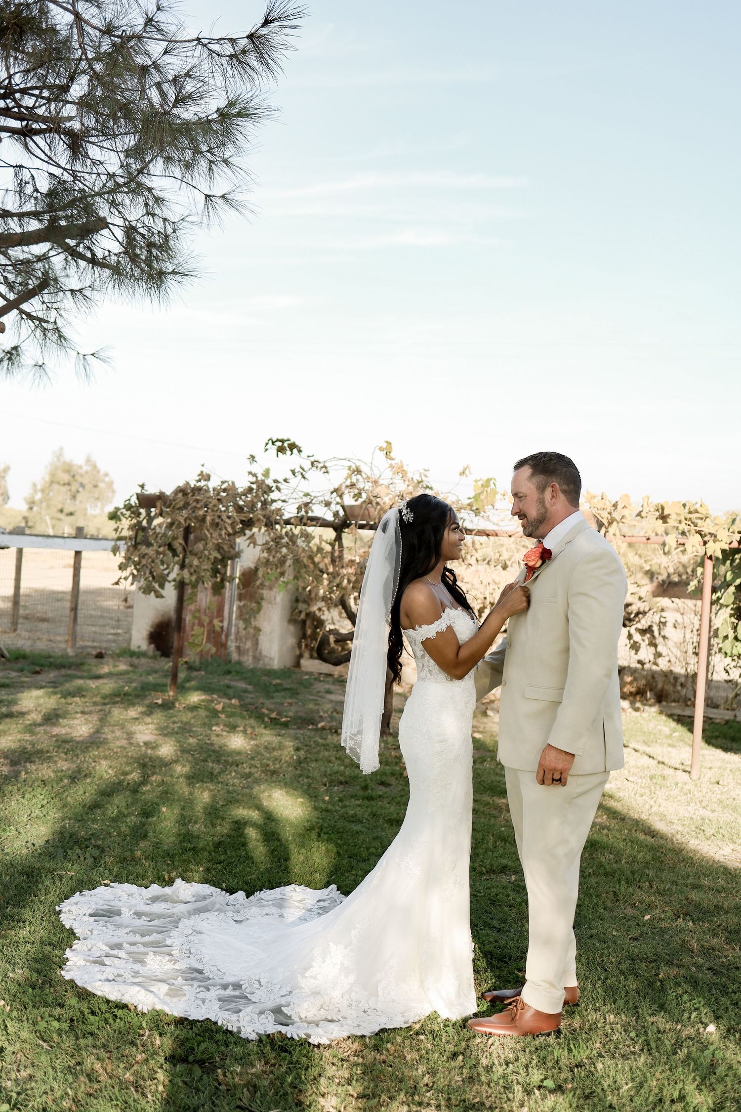 A couple shares a romantic moment in their wedding attire on a grassy hillside during golden hour.