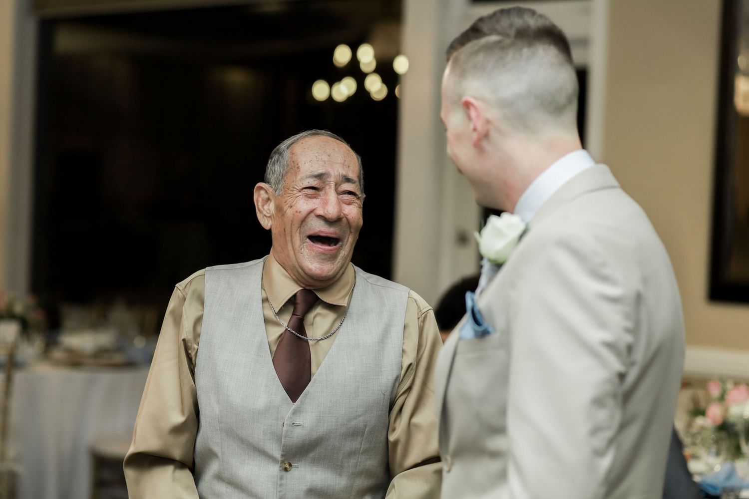 Candid moment of joyful laughter shared during wedding reception.