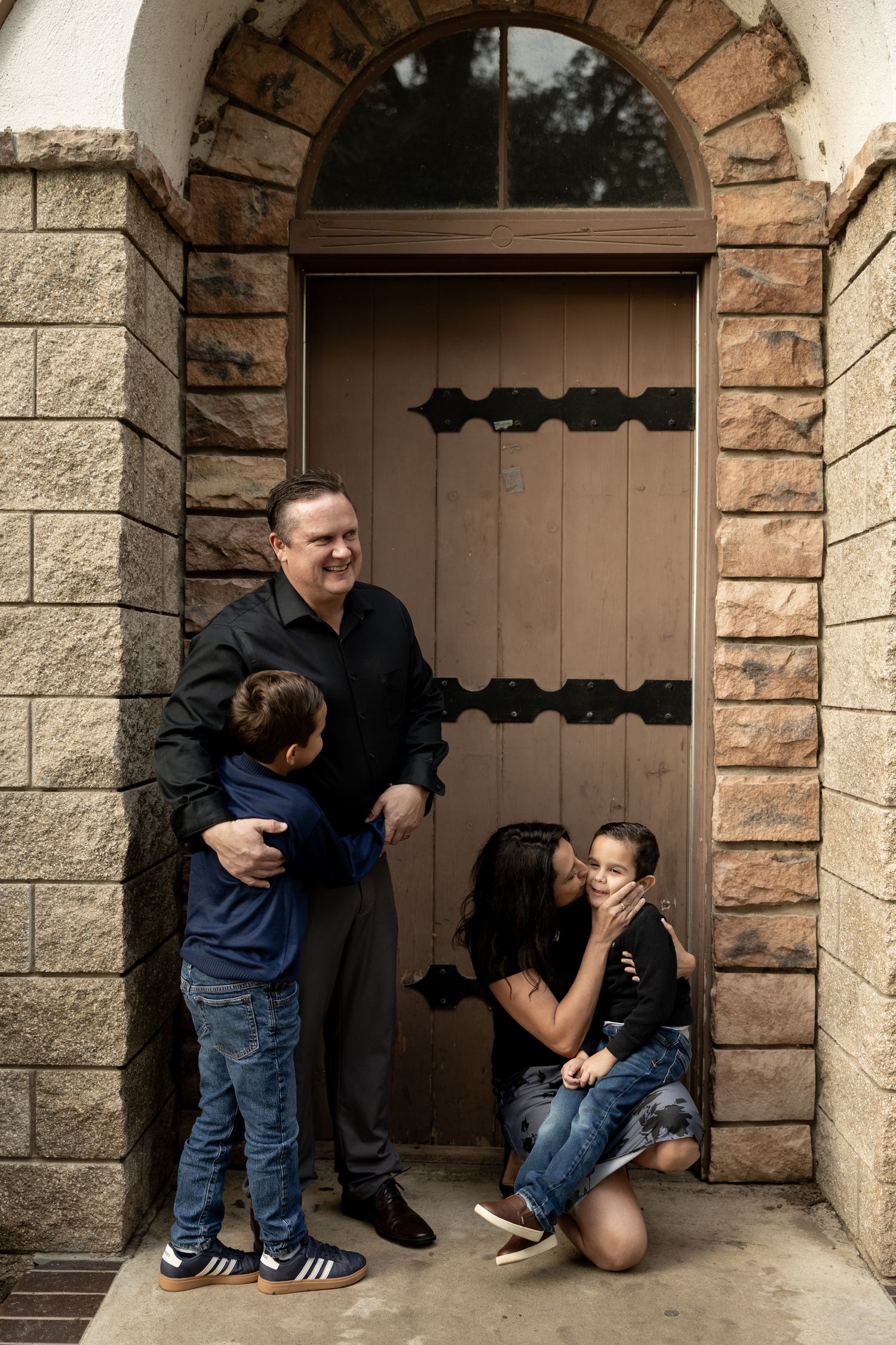 A series of four candid moments showing playful interaction between parent and child in a stone archway doorway.