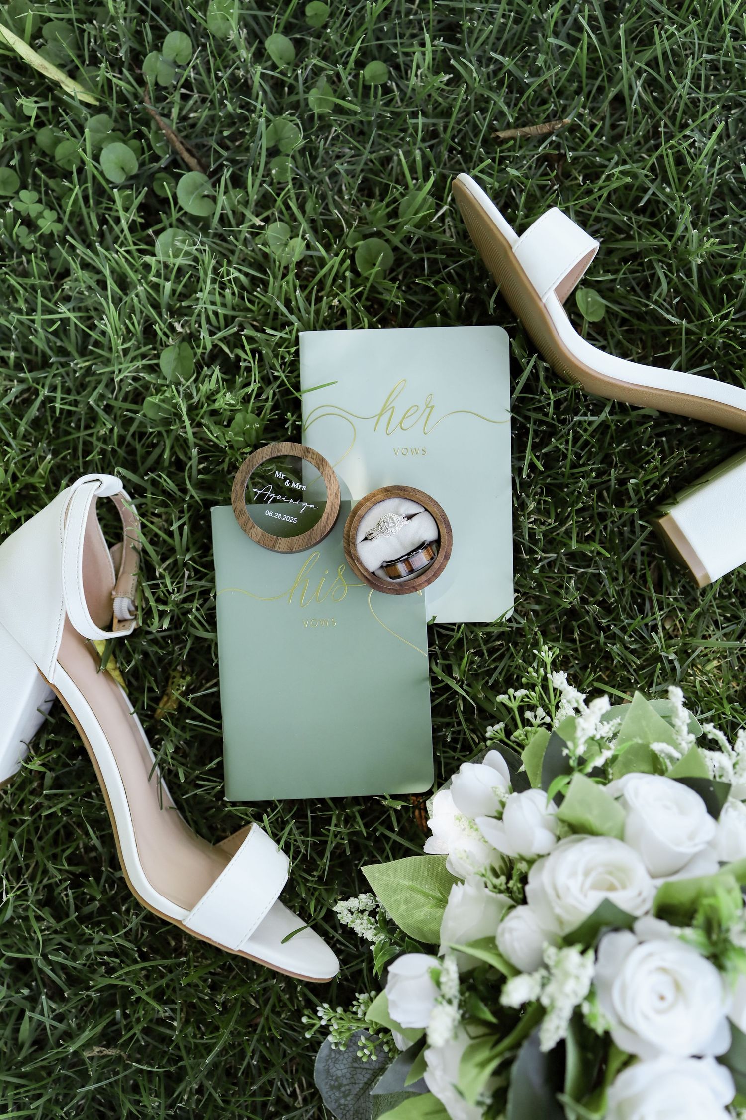 Wedding details including white heels, floral bouquet, and mint green place cards on grass.