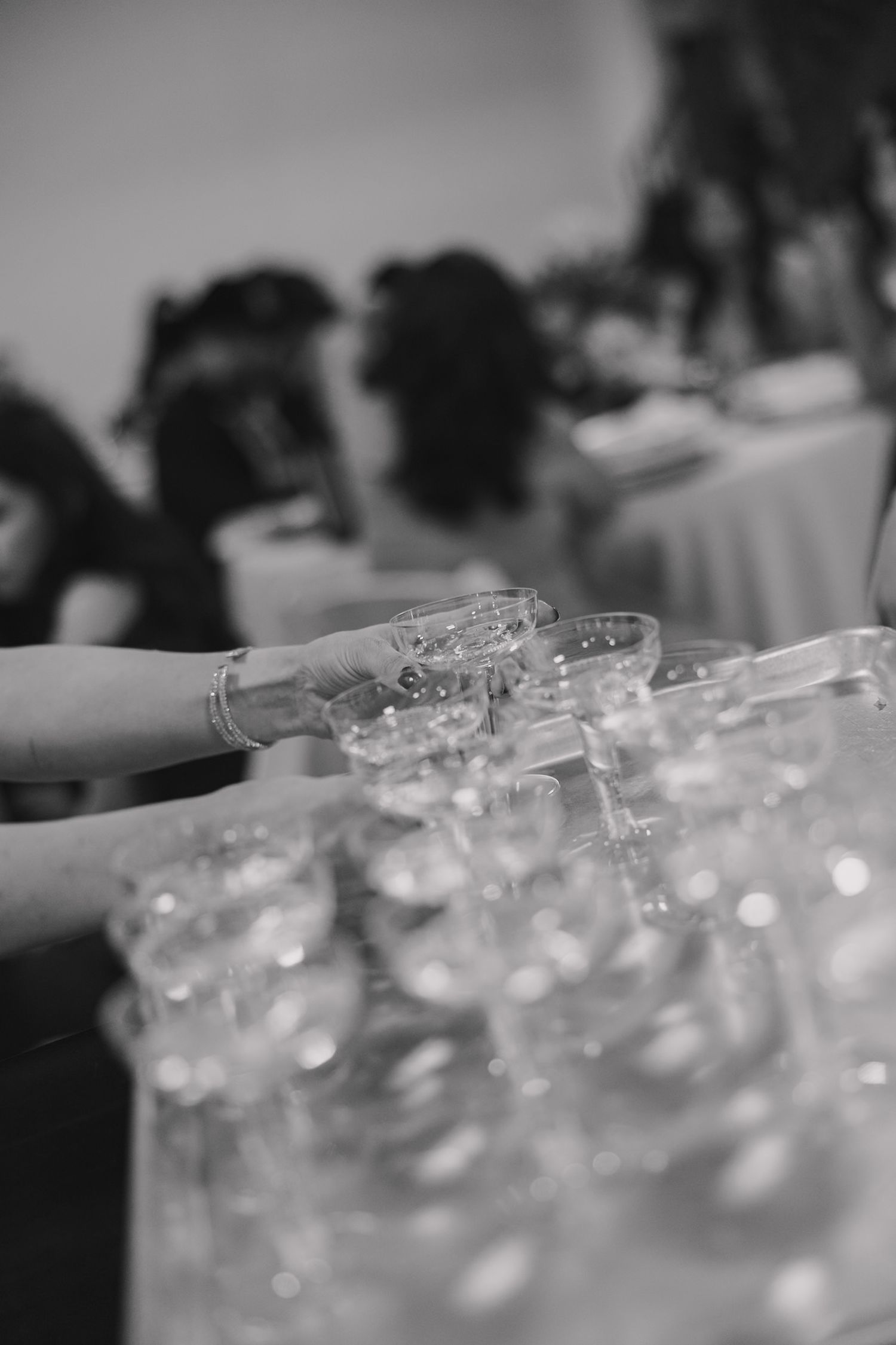 Black and white photo of elegant crystal glasses arranged on a tray at a formal event or wedding reception.