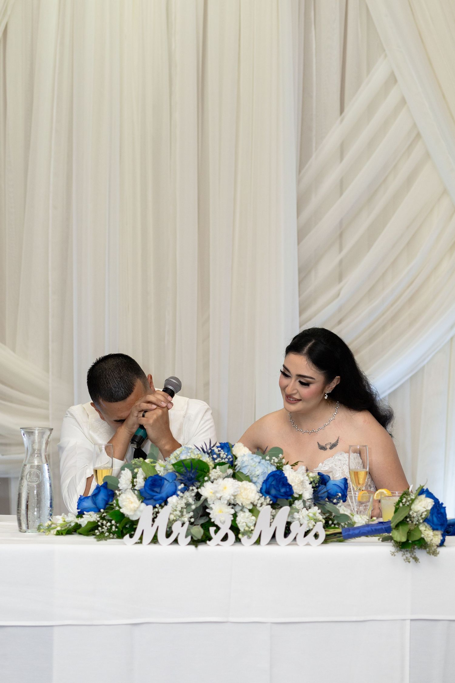 Wedding reception table decorated with blue and white flowers and Mr & Mrs signage.
