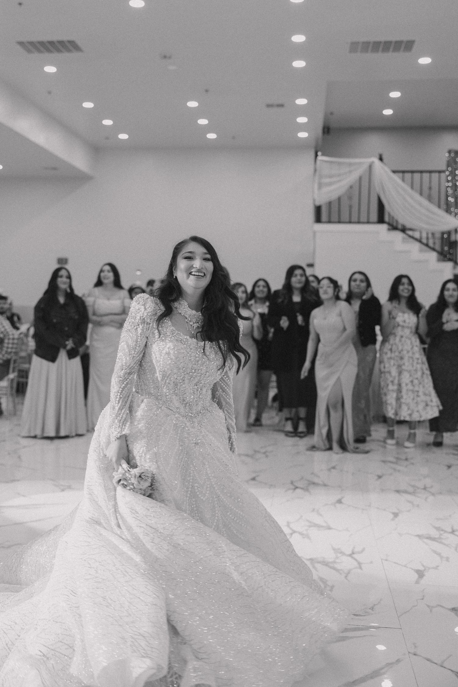 Flowing white ballgown wedding dress with lace details twirls on a bright dance floor.