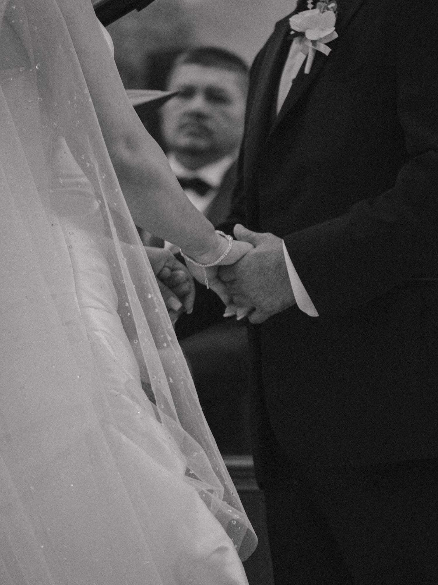 Black and white photo of wedding ceremony hands clasped together during vows.